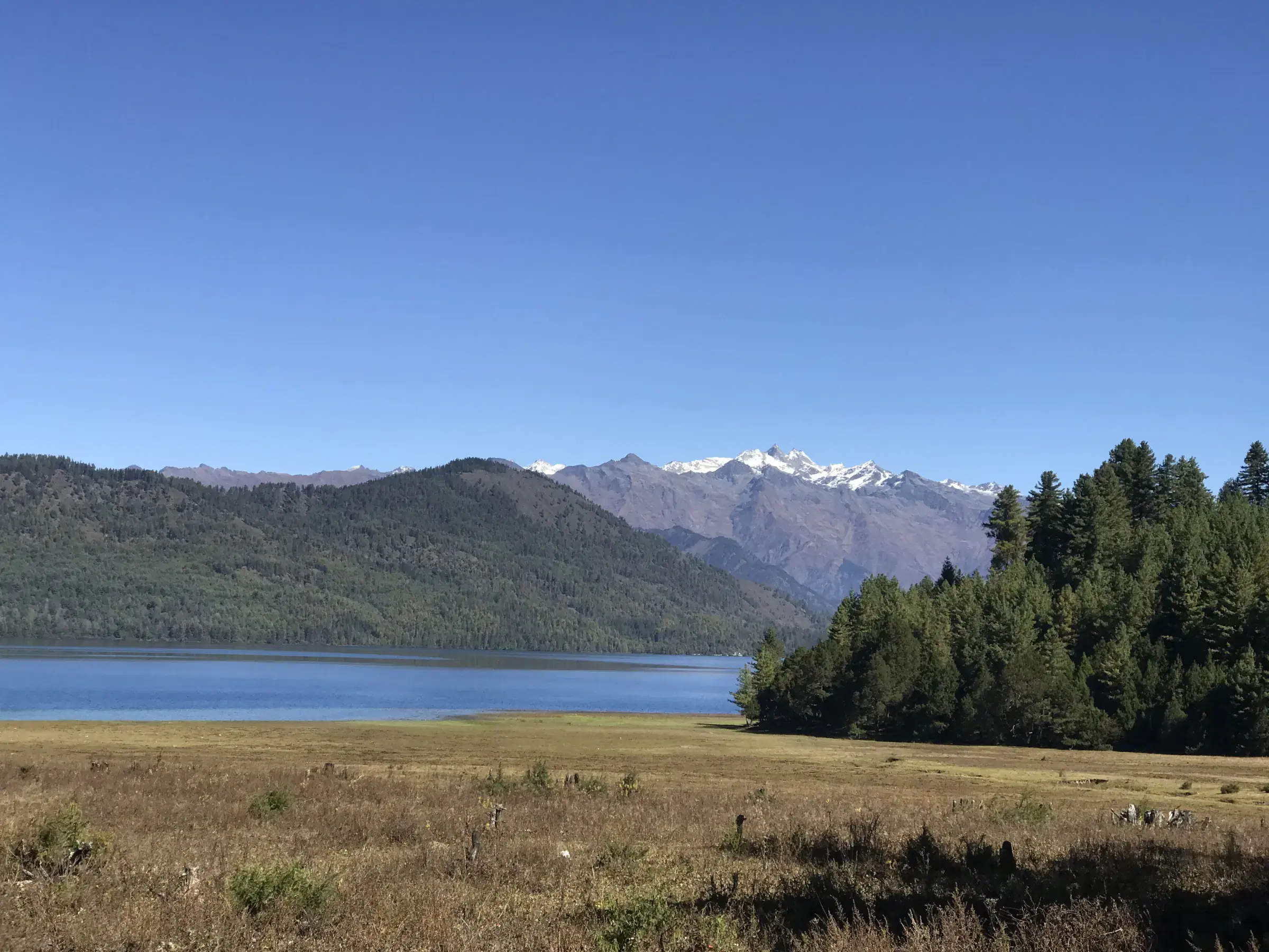 Mountain landscape featuring rocky terrain, water, blue sky, and greenery.
