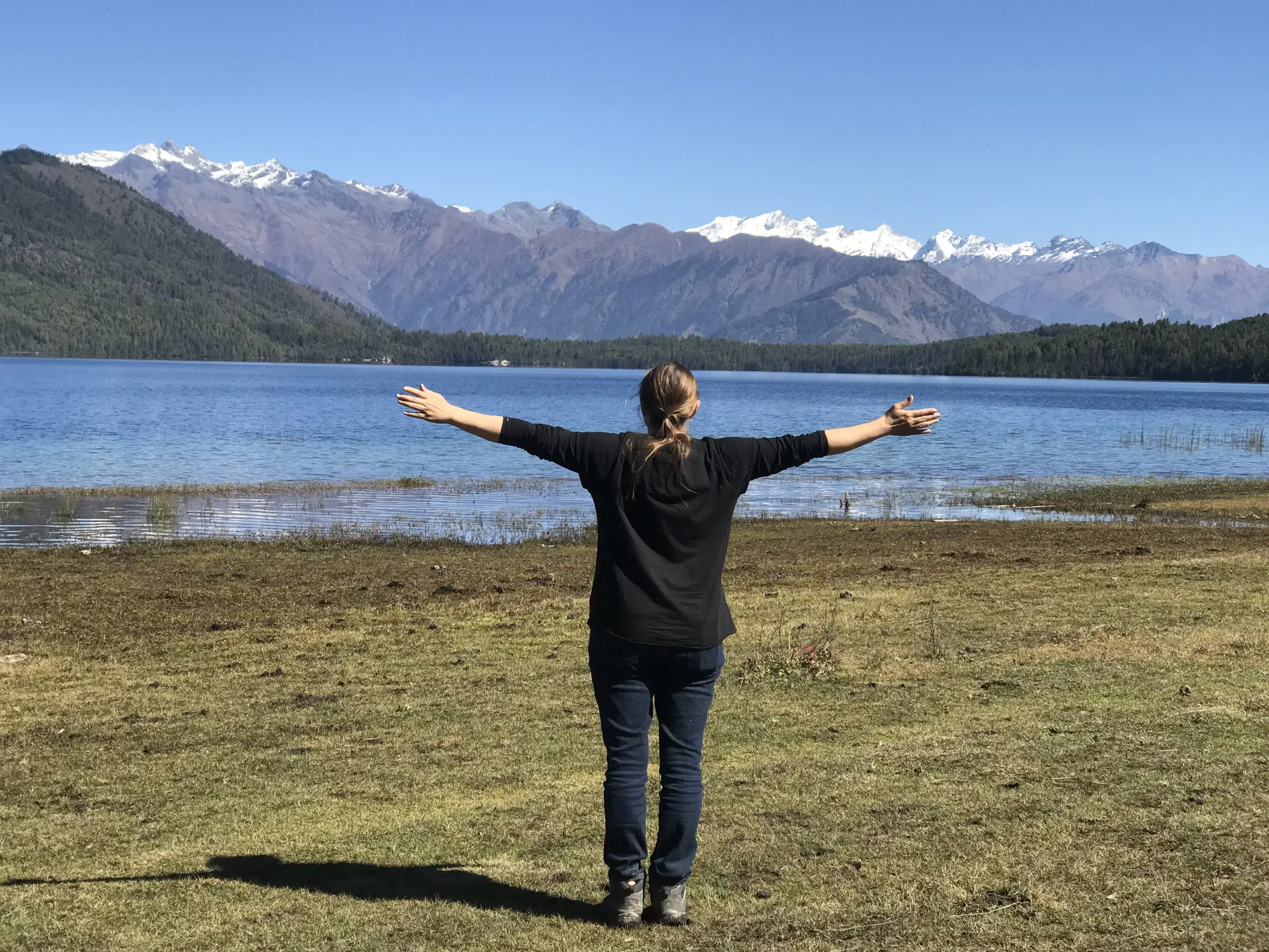 Outdoor scene featuring people, water, blue sky, and greenery.