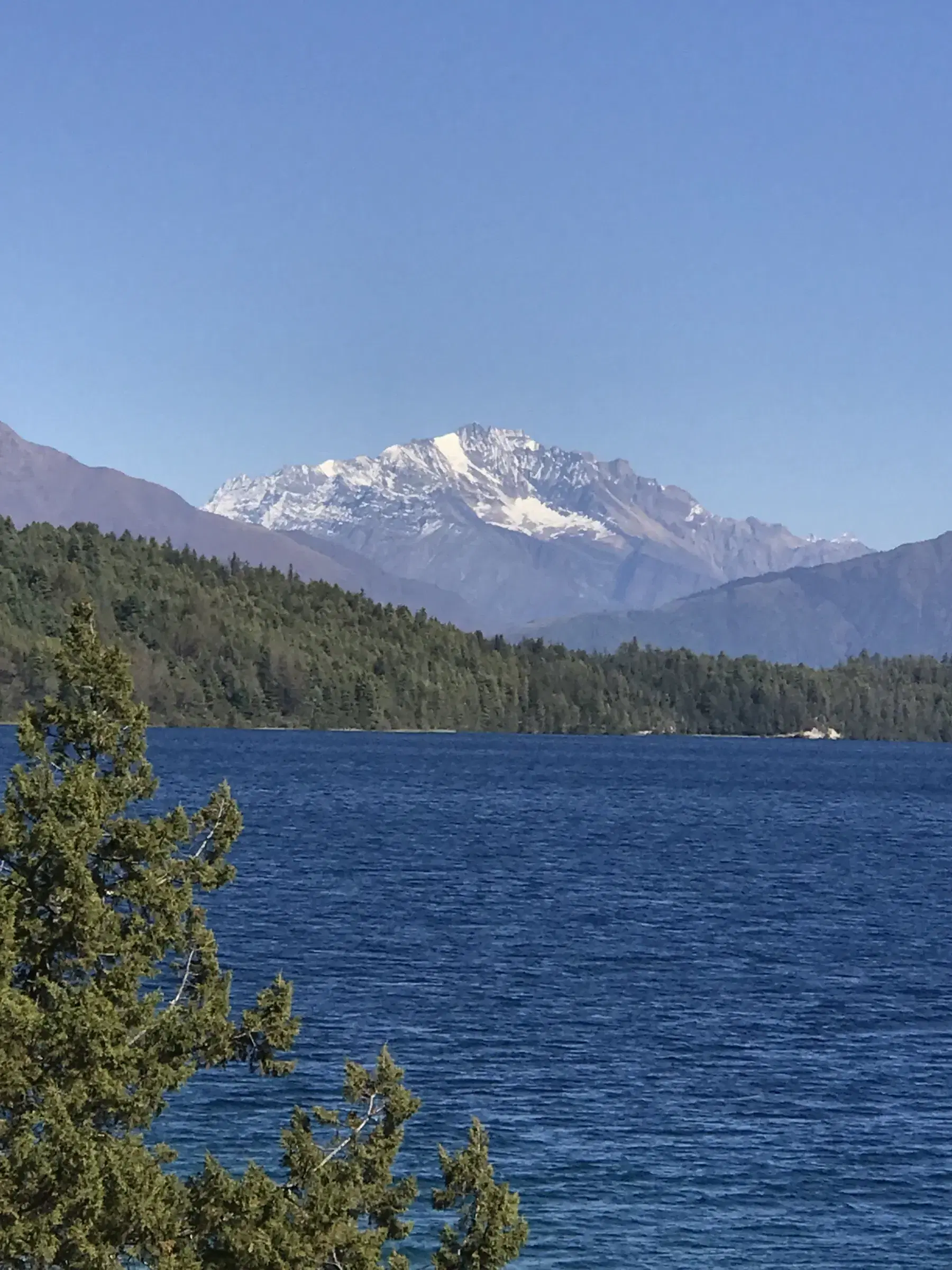 Mountain landscape featuring snowy terrain, water, and blue sky.