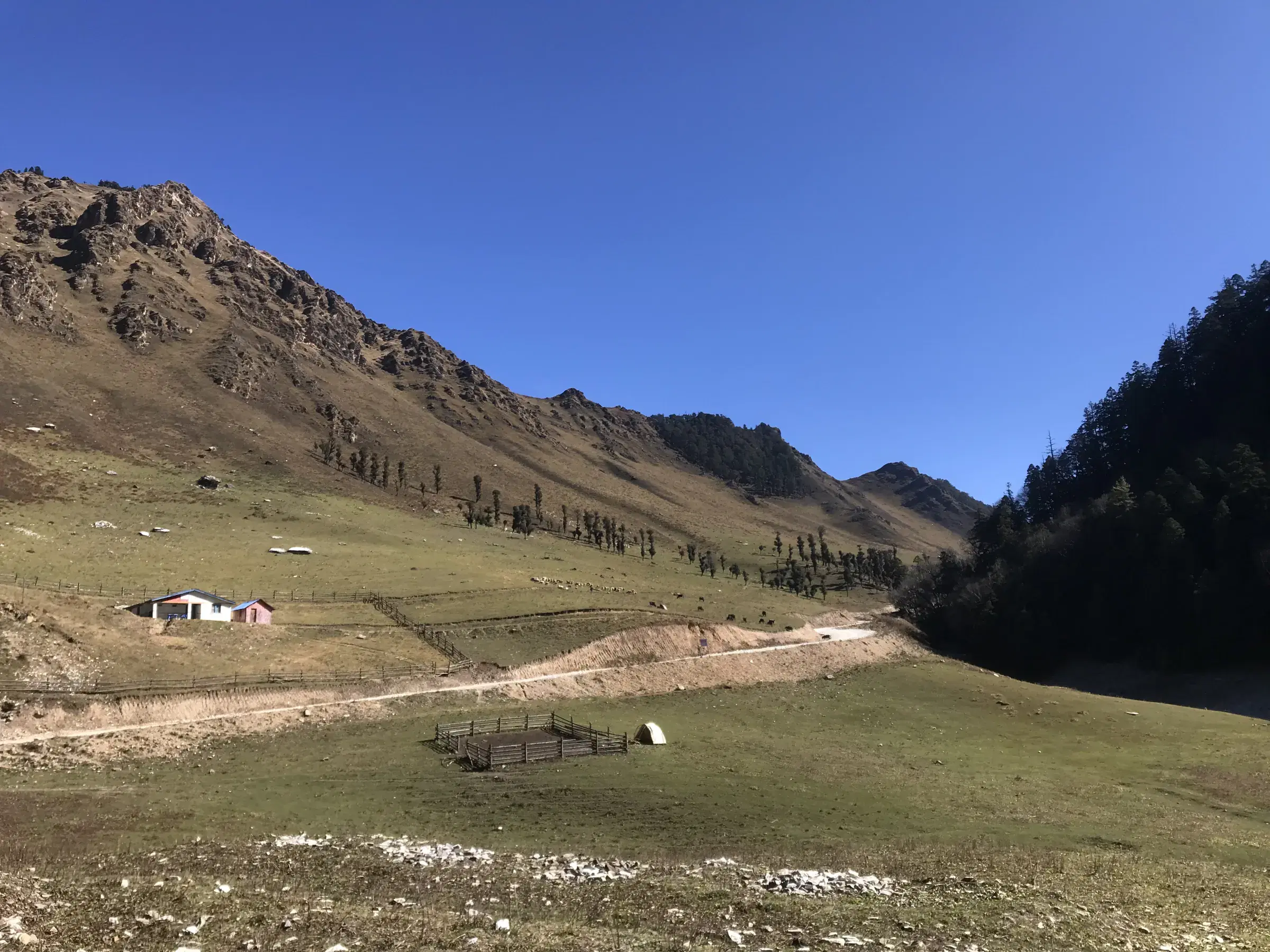 Mountain landscape featuring rocky terrain, blue sky, and greenery.