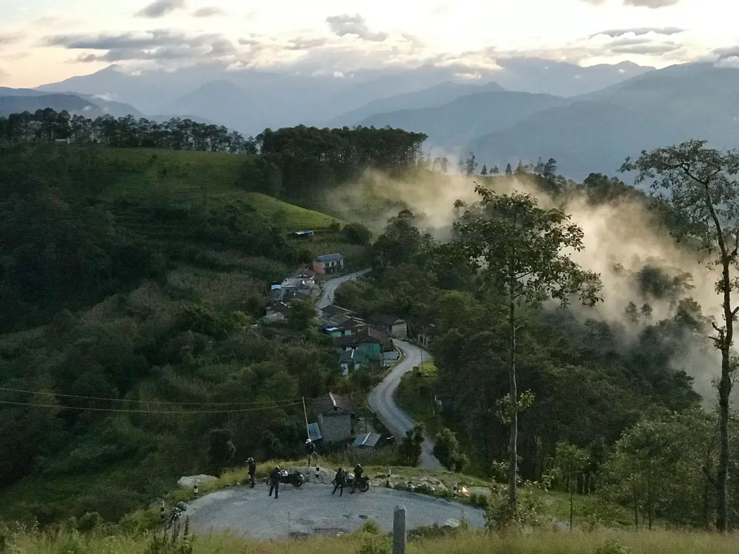 Mountain landscape featuring rocky terrain, cloudy sky, and greenery.