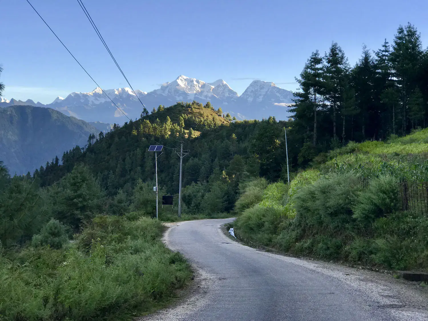 Mountain landscape featuring rocky terrain, blue sky, and greenery.