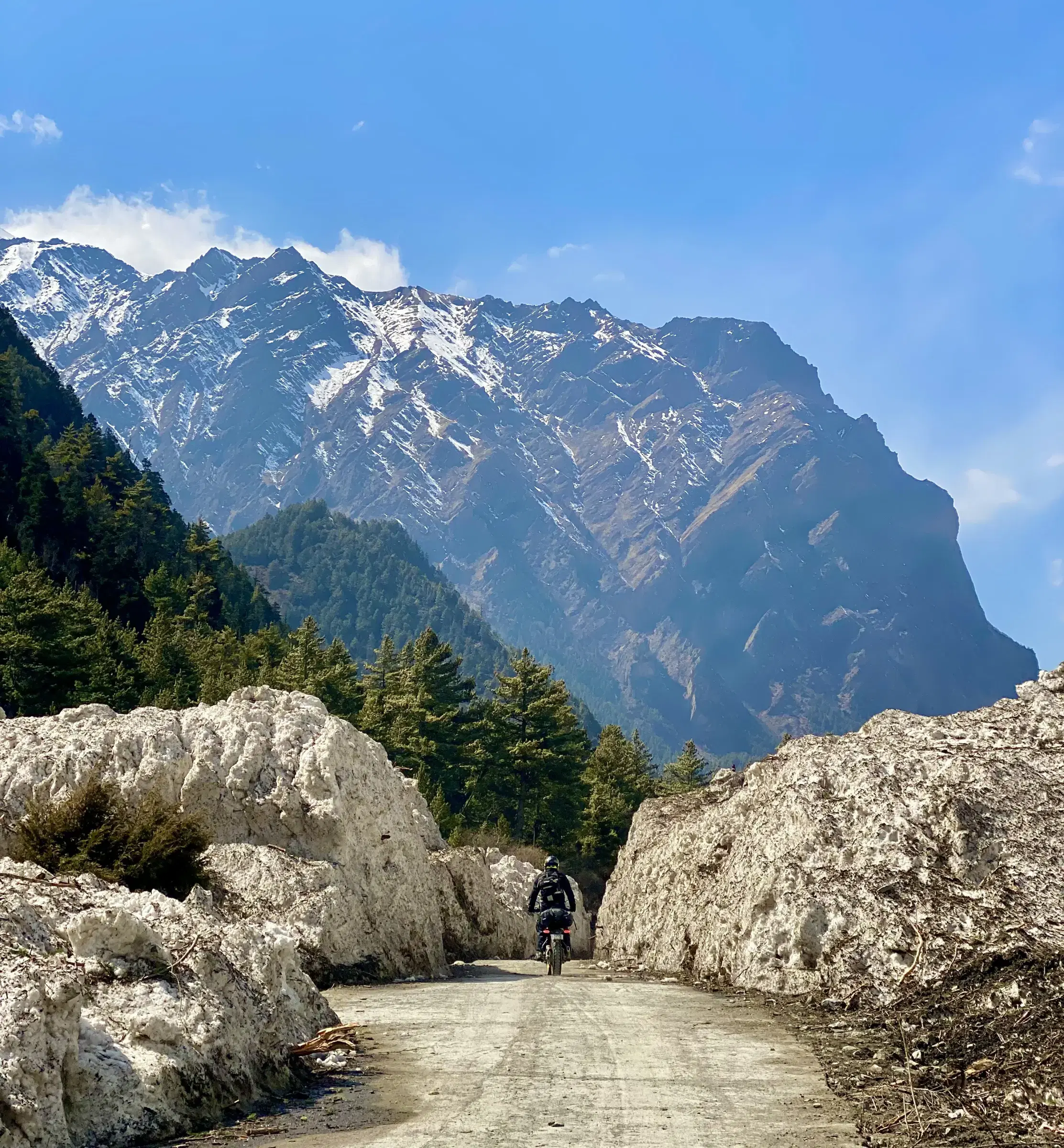 Mountain landscape featuring rocky terrain, water, a built structure, and cloudy sky.