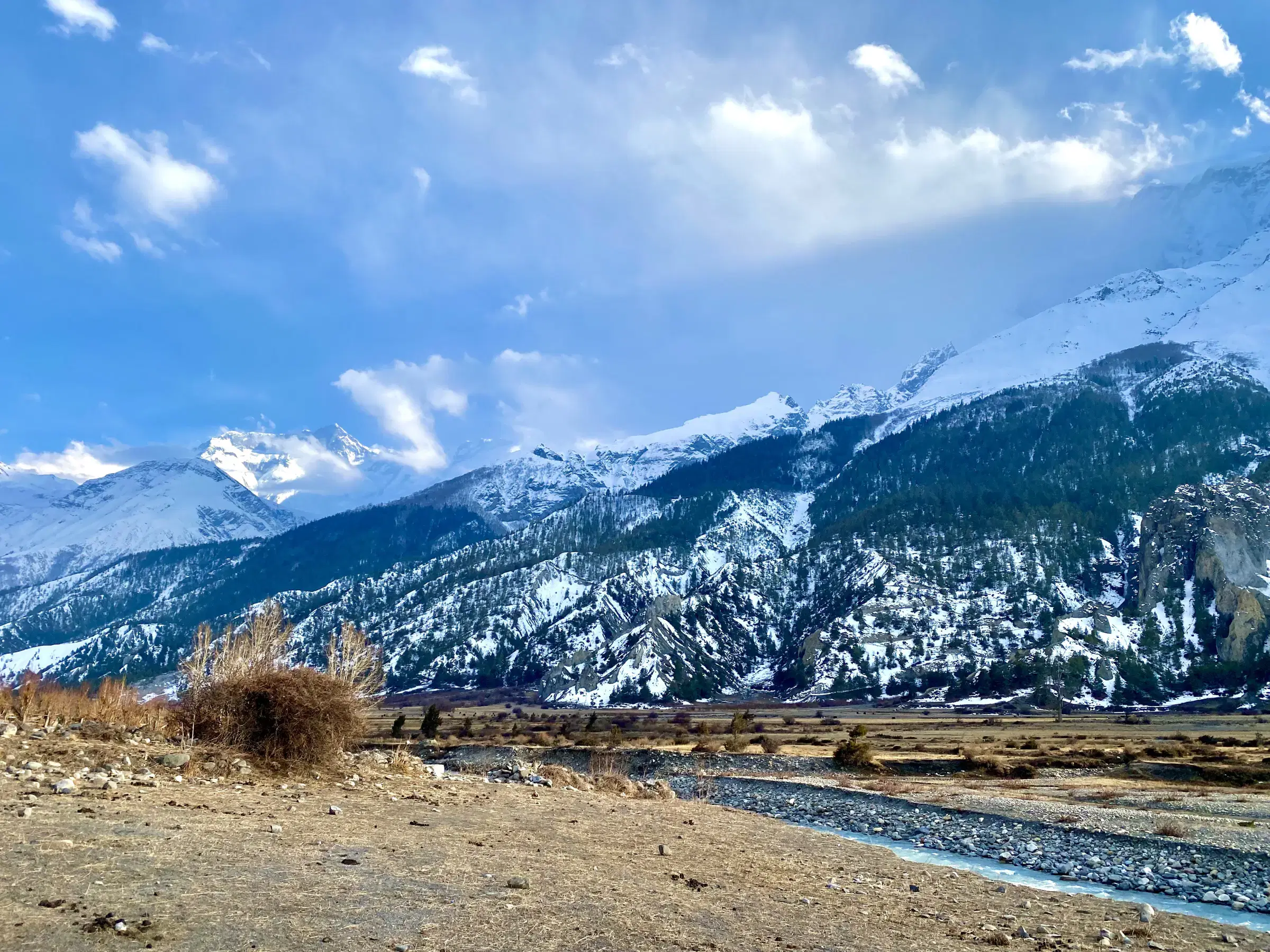 Mountain landscape featuring snowy terrain, water, and cloudy sky.