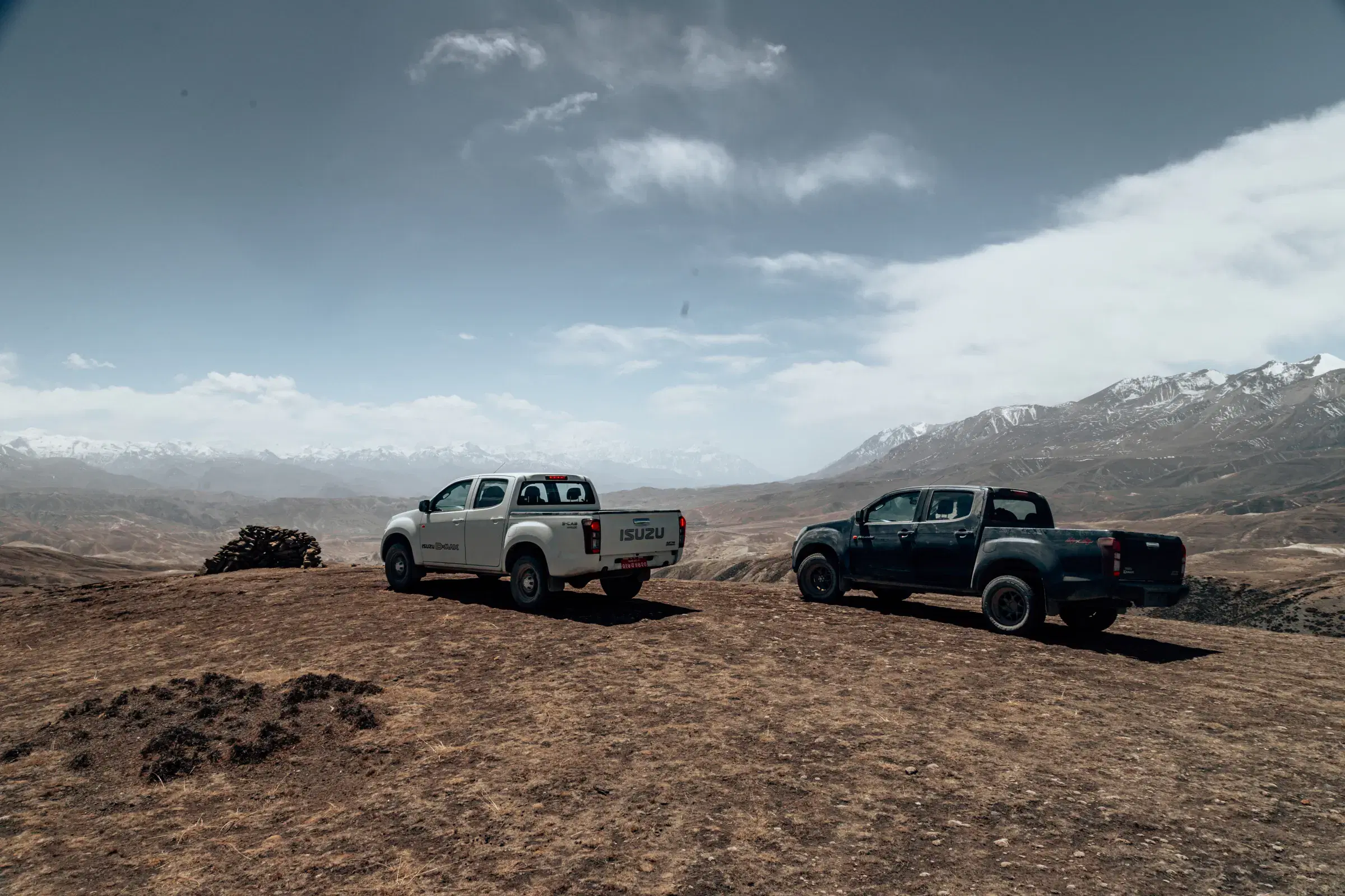 Outdoor vehicle scene featuring a vehicle, rocky terrain, and cloudy sky.