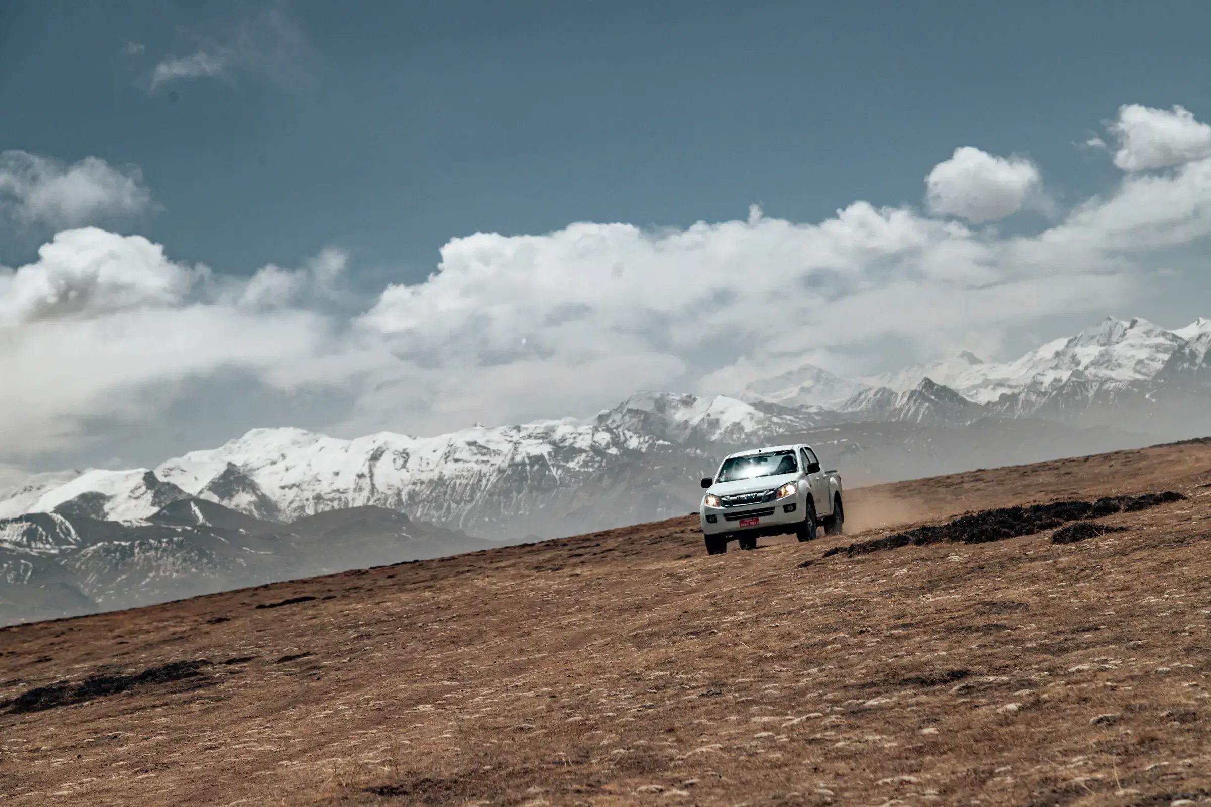 Mountain landscape featuring snowy terrain, water, and cloudy sky.