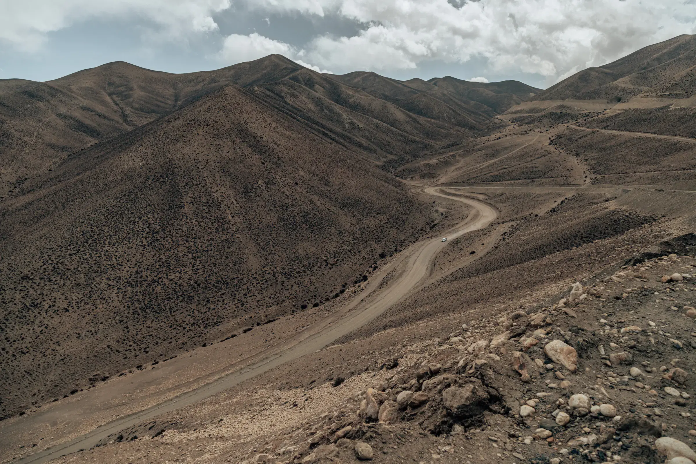 Mountain landscape featuring rocky terrain, a built structure, and cloudy sky.