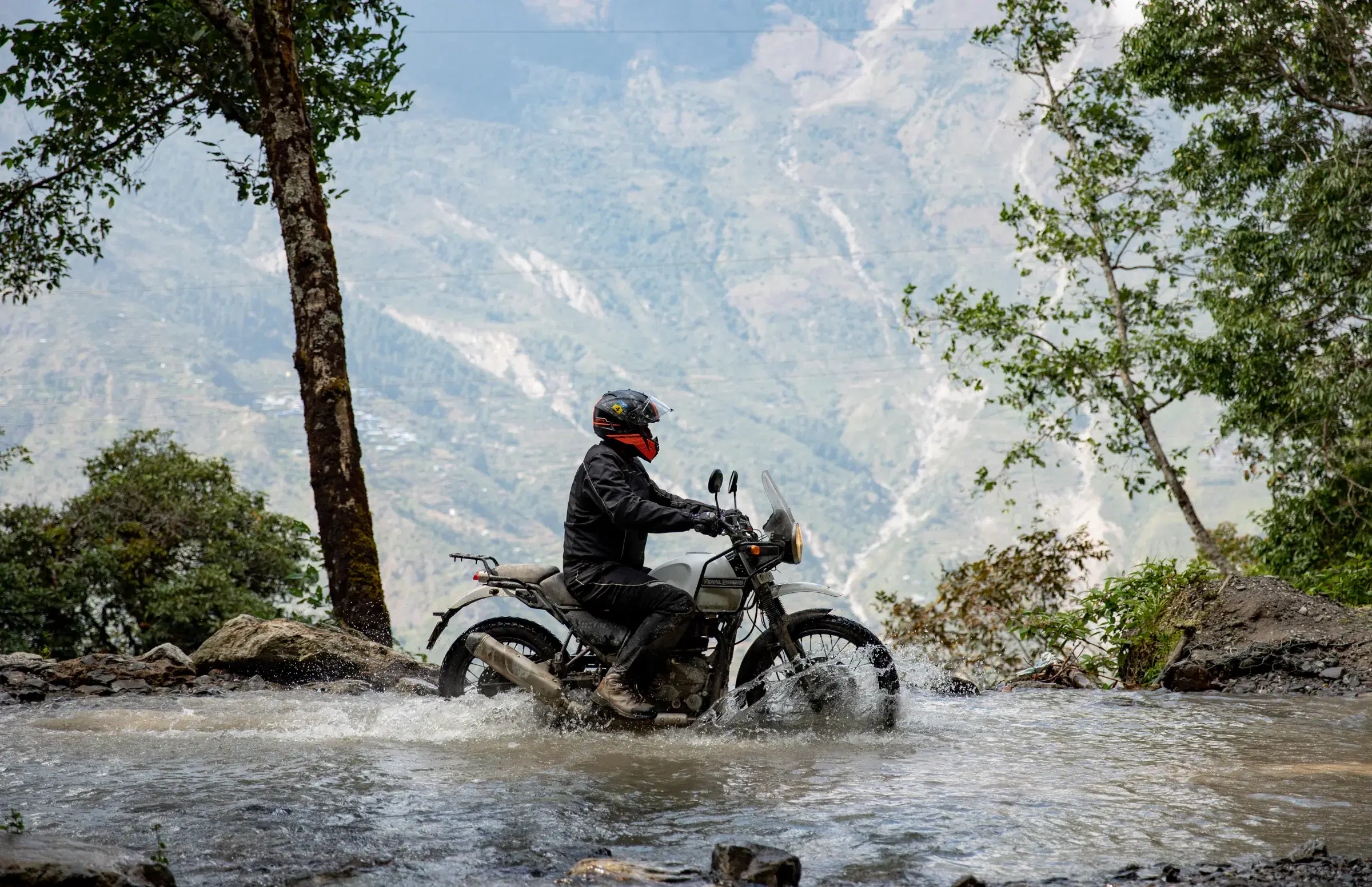 Outdoor scene featuring people, rocky terrain, a built structure, and cloudy sky.