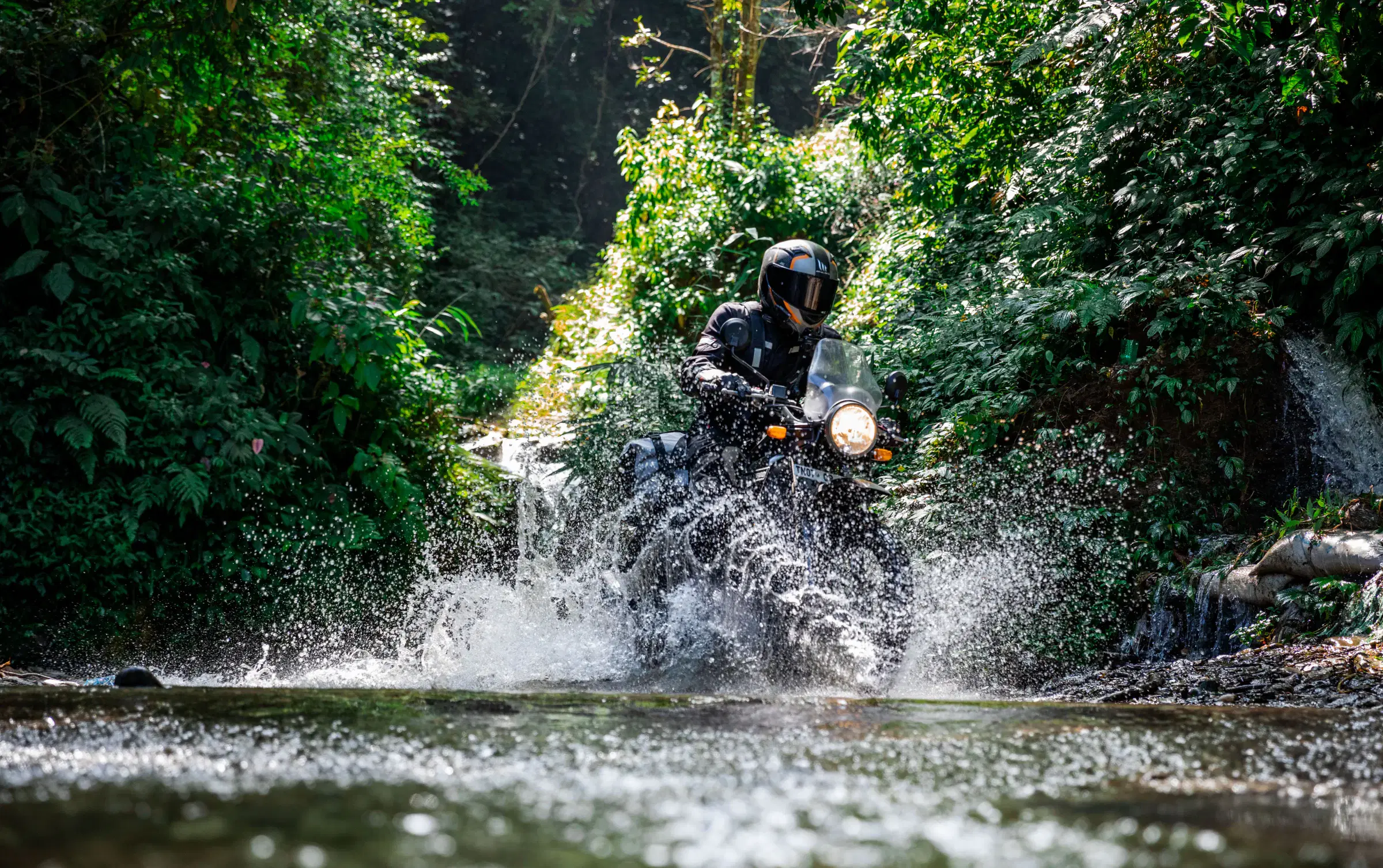 Outdoor adventure scene featuring people, a vehicle, rocky terrain, a built structure, and greenery.