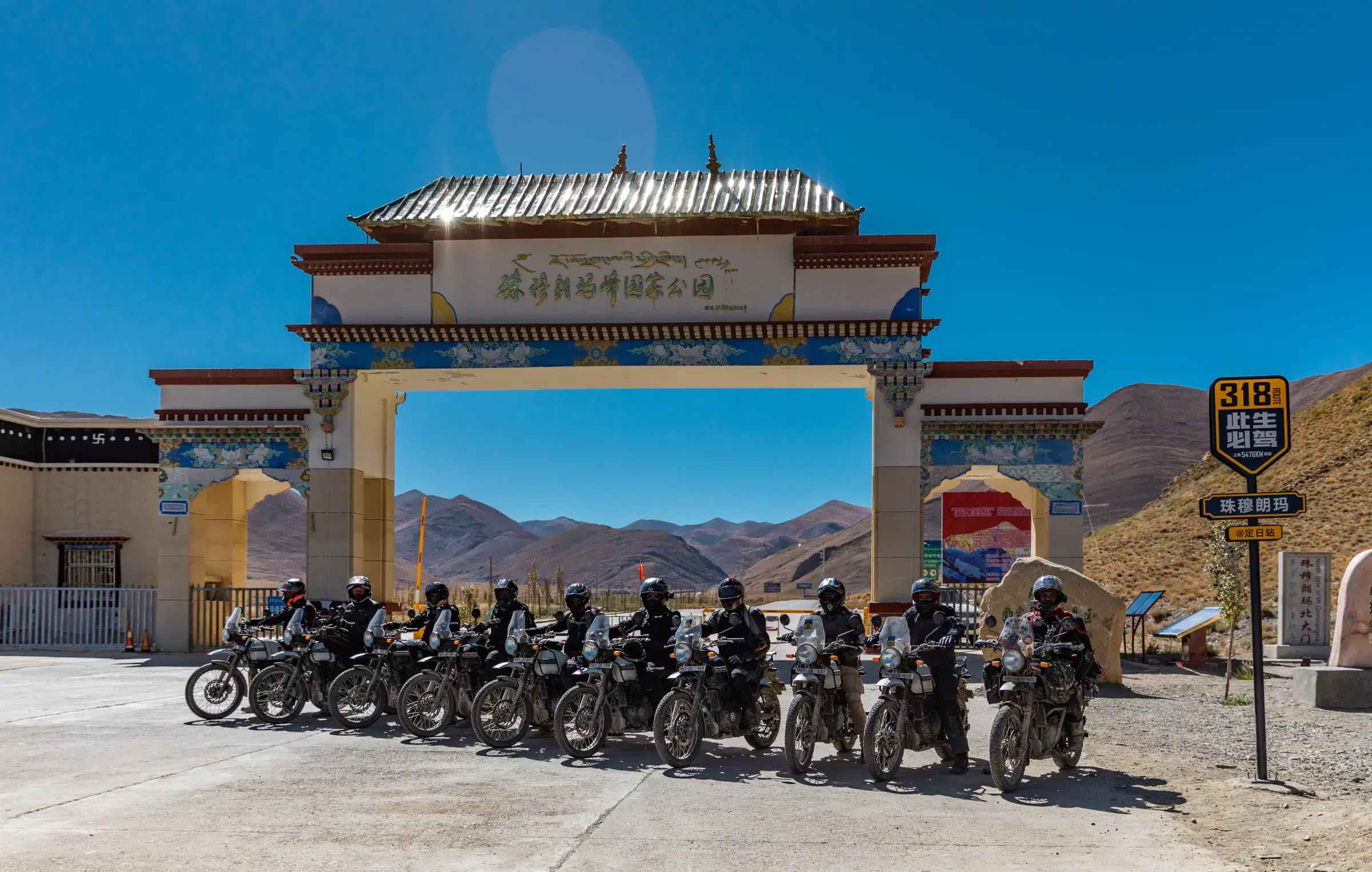 Outdoor scene featuring people, rocky terrain, a built structure, and blue sky.
