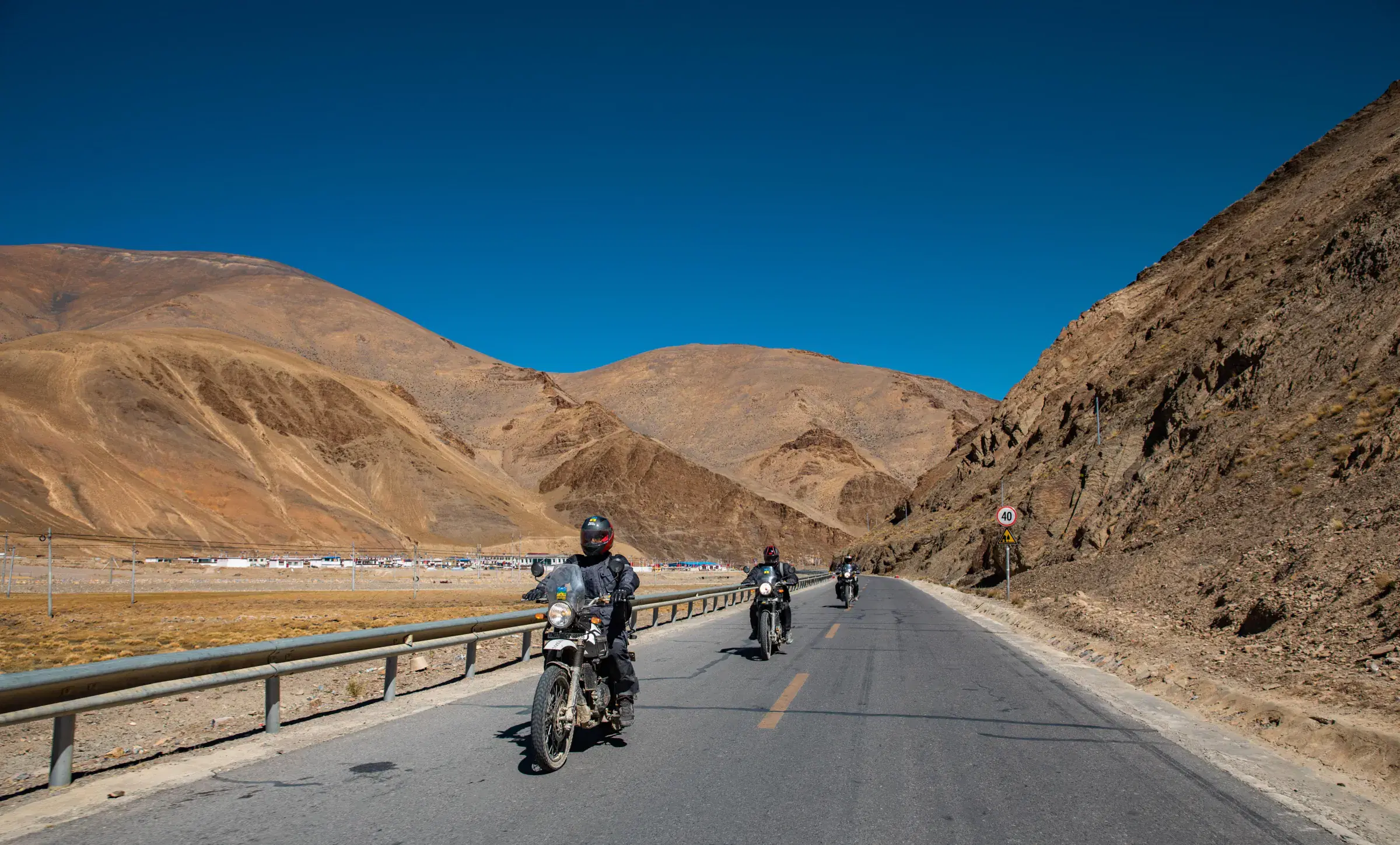 Outdoor scene featuring people, rocky terrain, a built structure, and blue sky.