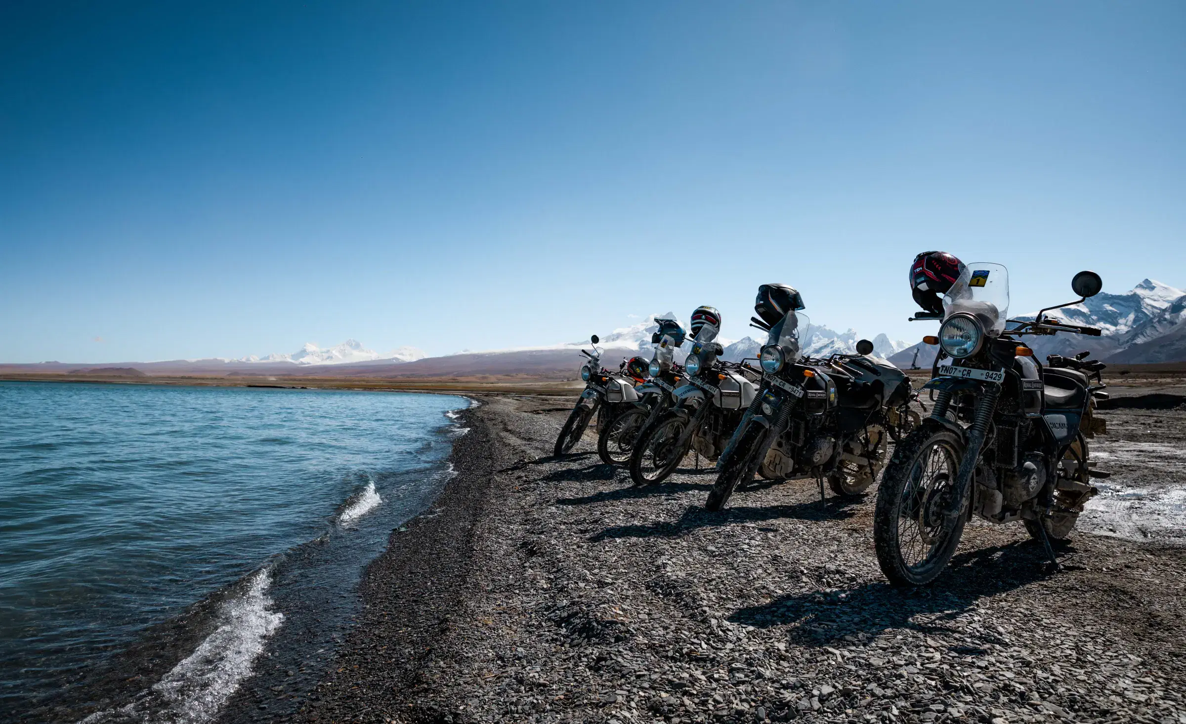 Outdoor adventure scene featuring people, a vehicle, rocky terrain, a built structure, and blue sky.