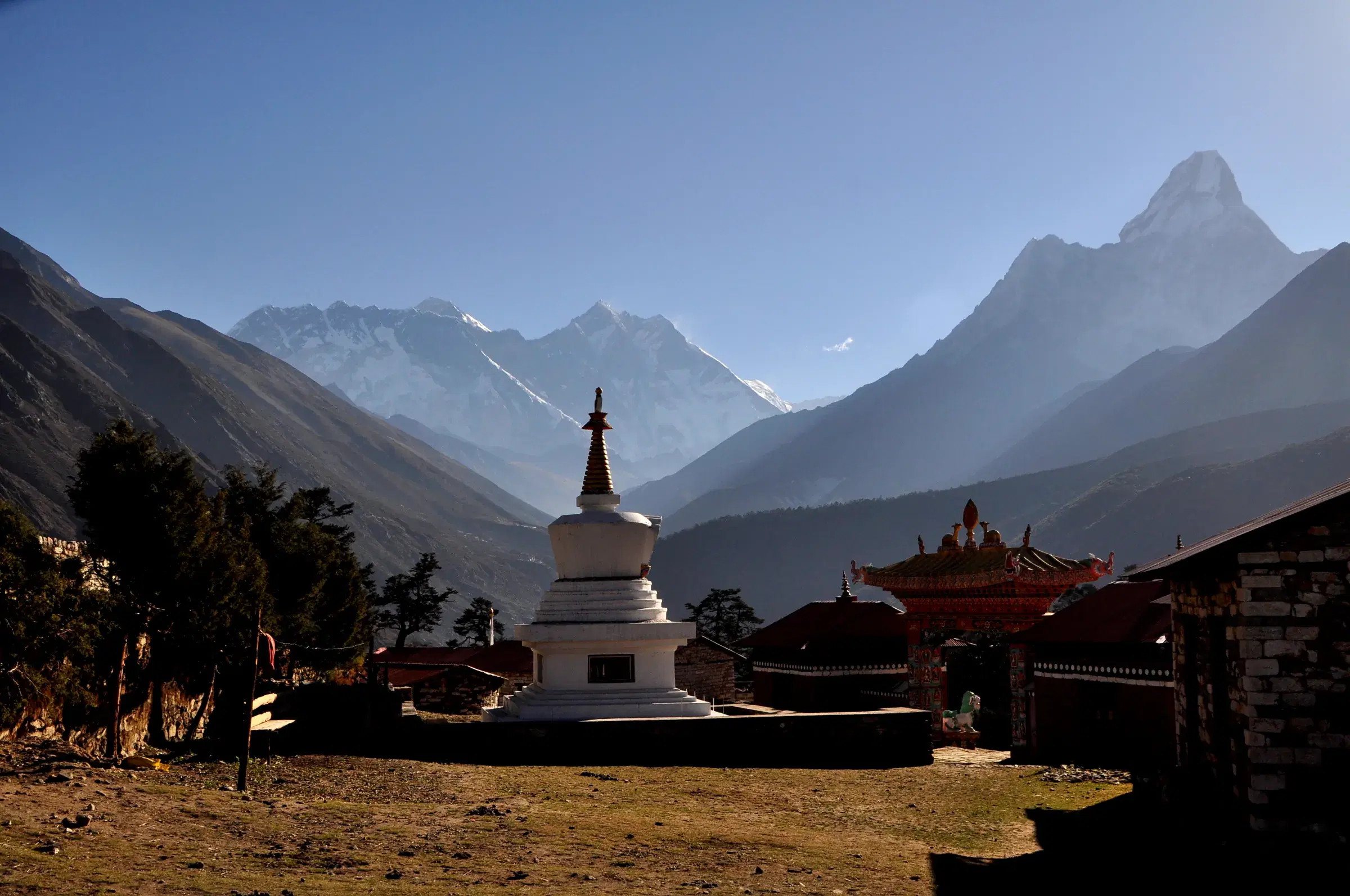 Mountain landscape featuring rocky terrain, a built structure, blue sky, and greenery.
