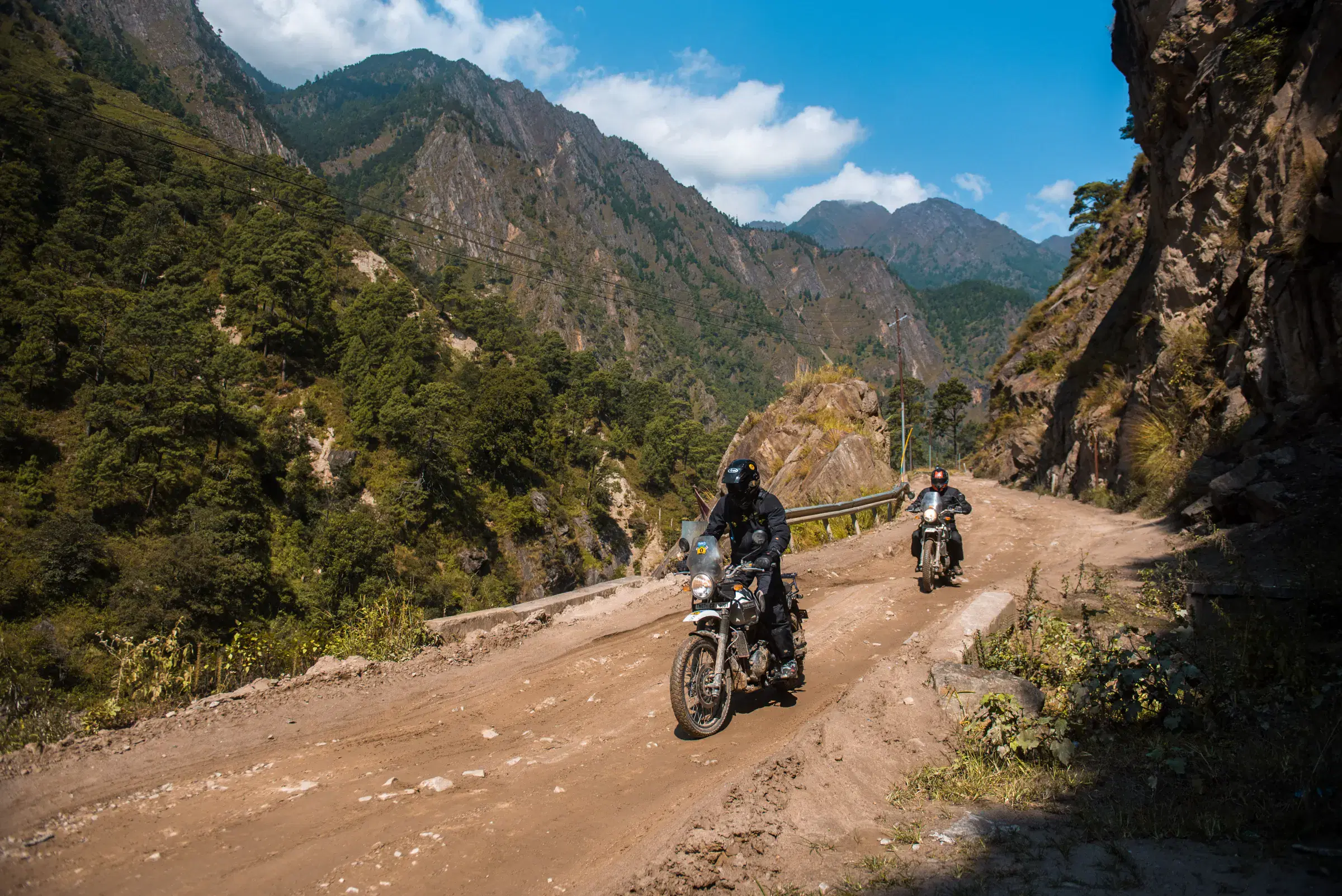 Outdoor vehicle scene featuring a vehicle, rocky terrain, and cloudy sky.