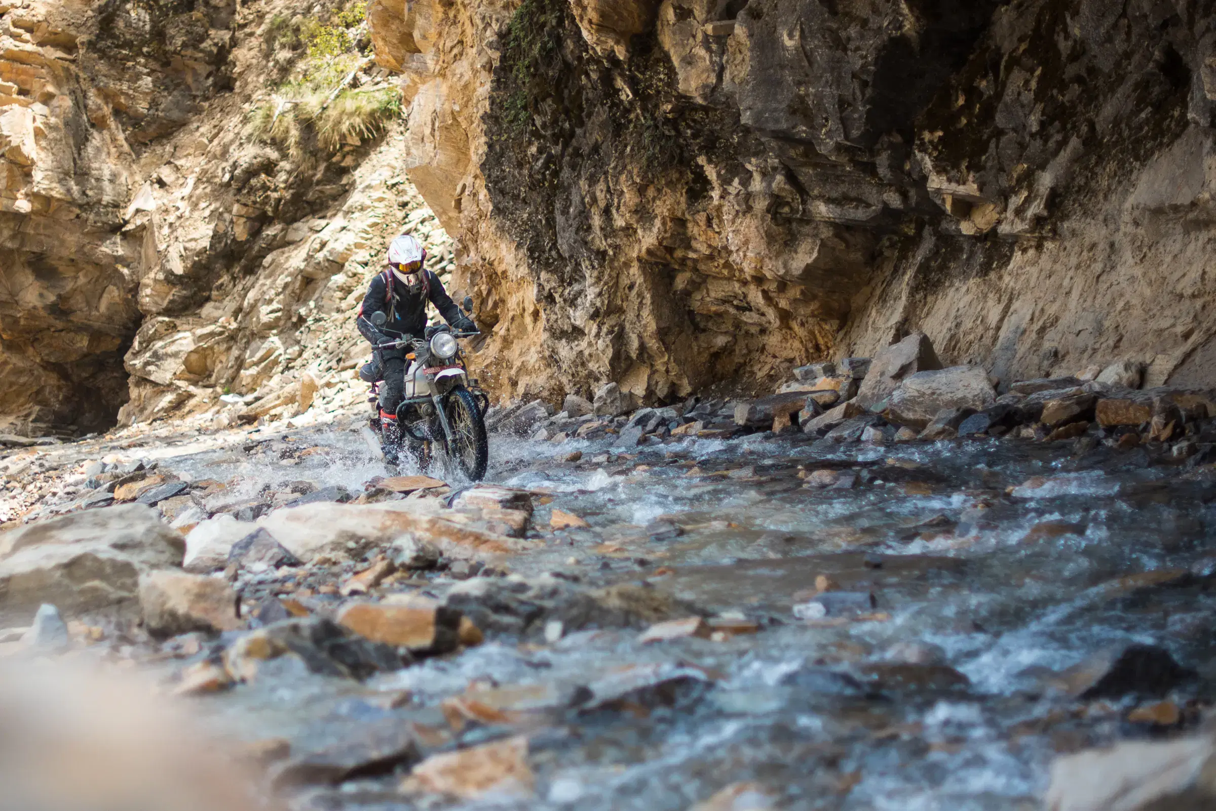 Outdoor scene featuring people, rocky terrain, and a built structure.