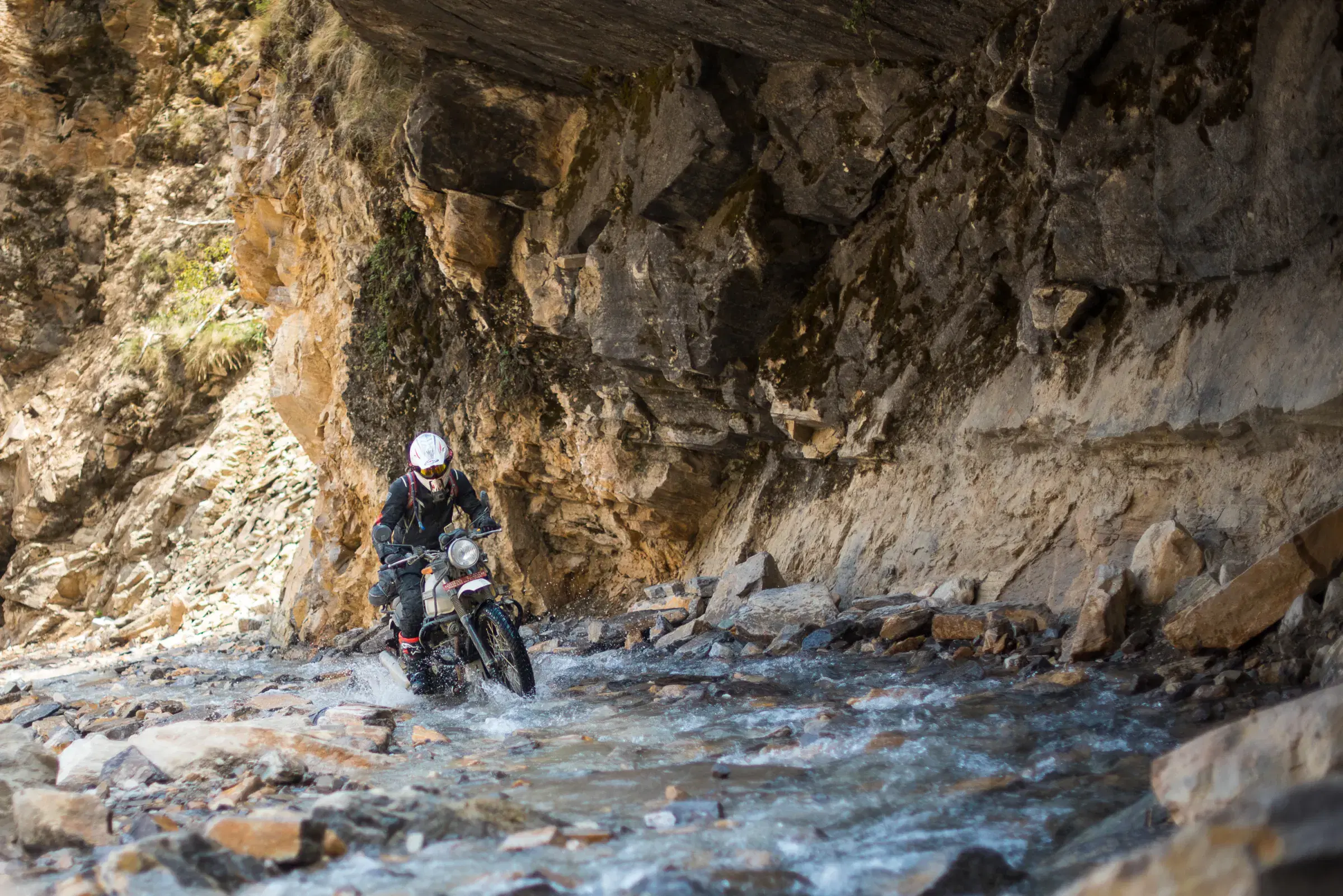 Outdoor scene featuring people, rocky terrain, and a built structure.
