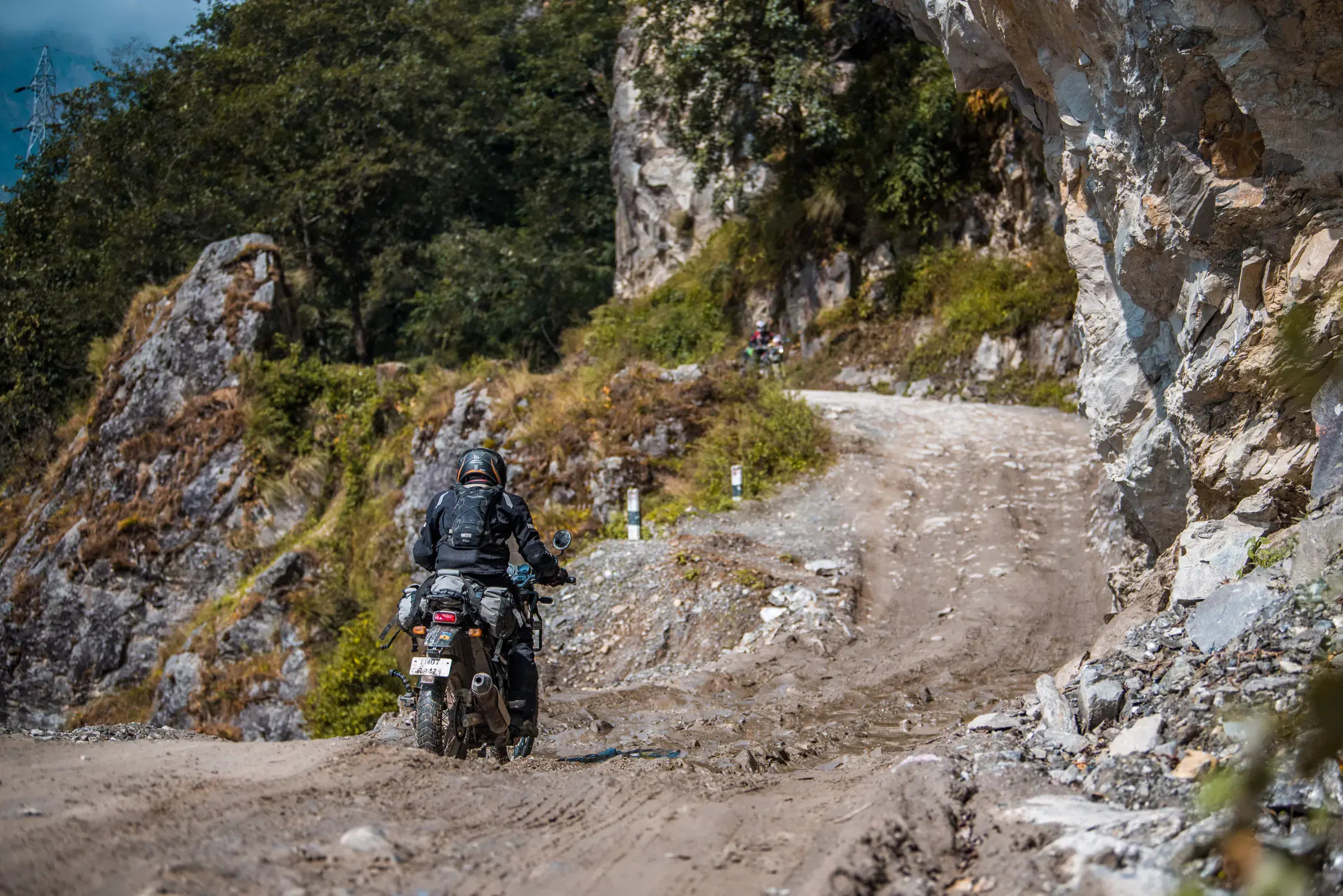 Outdoor adventure scene featuring people, a vehicle, rocky terrain, and a built structure.