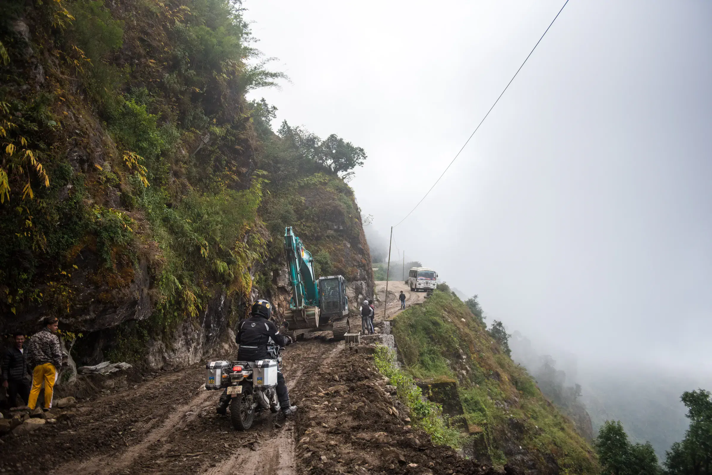 Outdoor scene featuring people, rocky terrain, a built structure, and open sky.