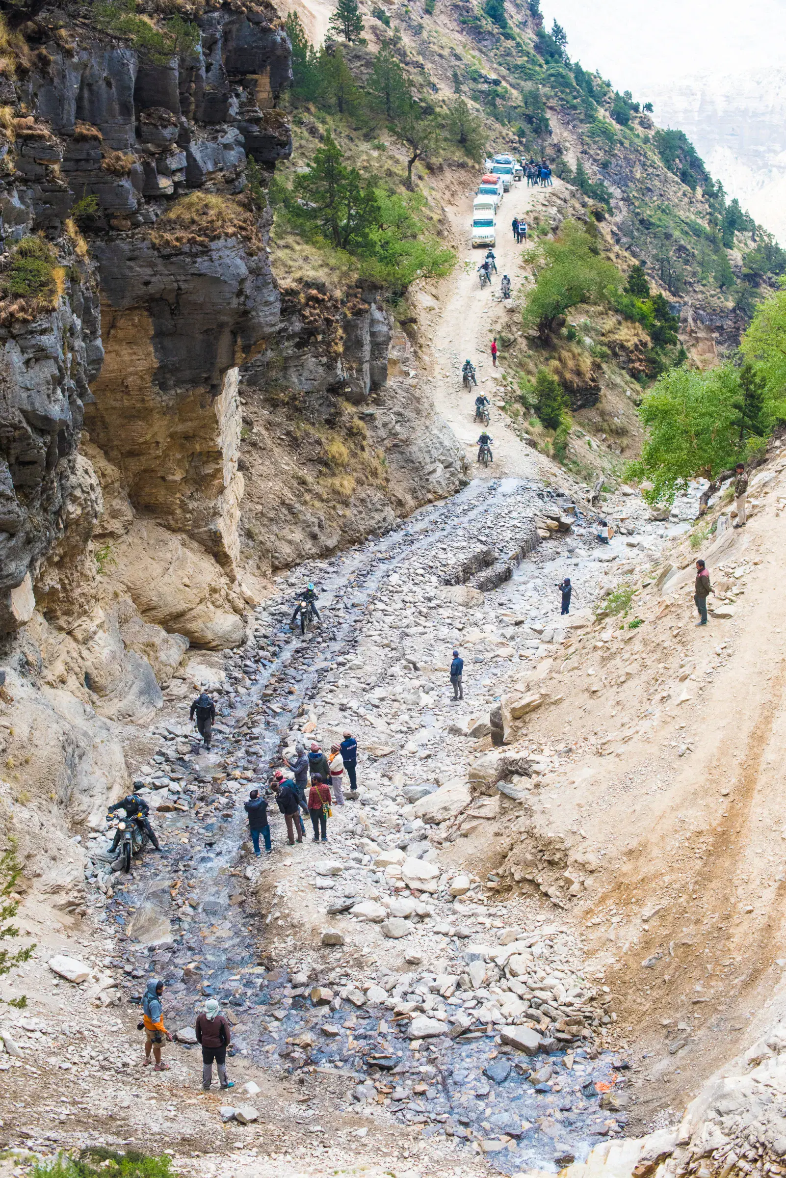 Portrait-oriented Outdoor scene featuring people, rocky terrain, and a built structure.