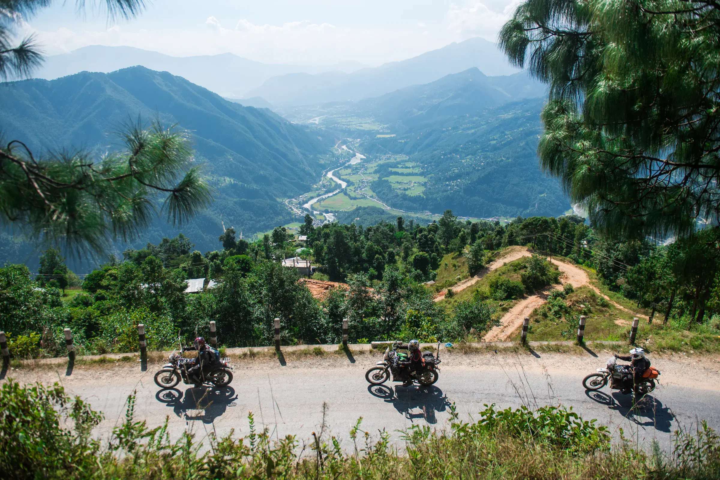 Outdoor vehicle scene featuring a vehicle, rocky terrain, cloudy sky, and greenery.