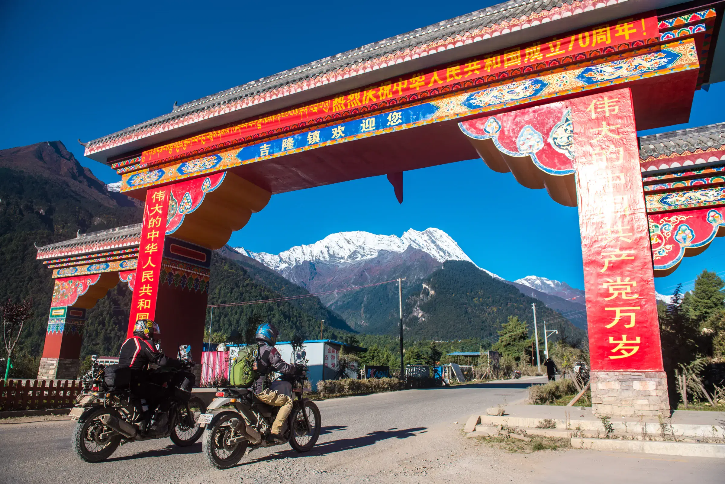 Outdoor adventure scene featuring people, a vehicle, rocky terrain, a built structure, and blue sky.