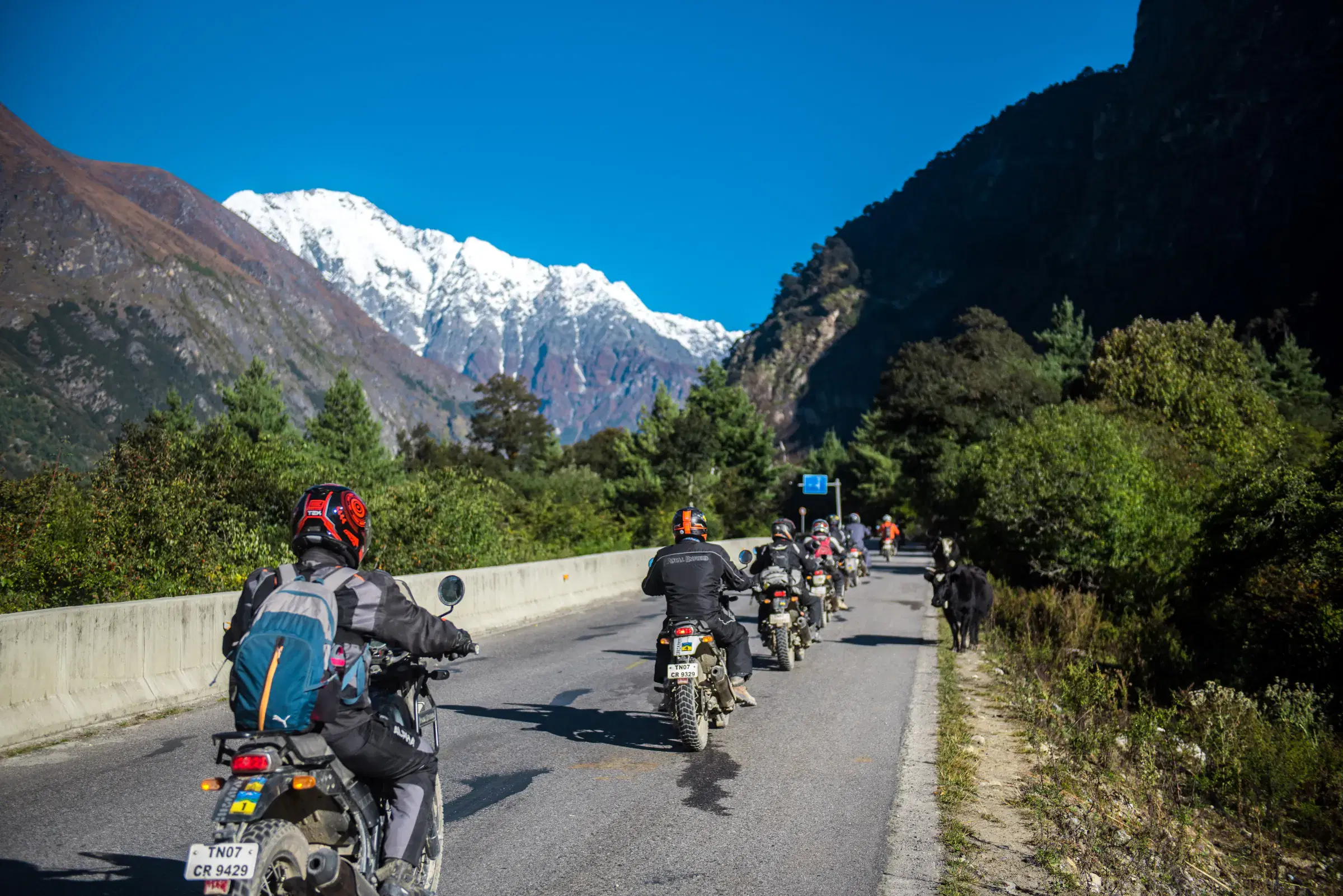Outdoor adventure scene featuring people, a vehicle, rocky terrain, and blue sky.