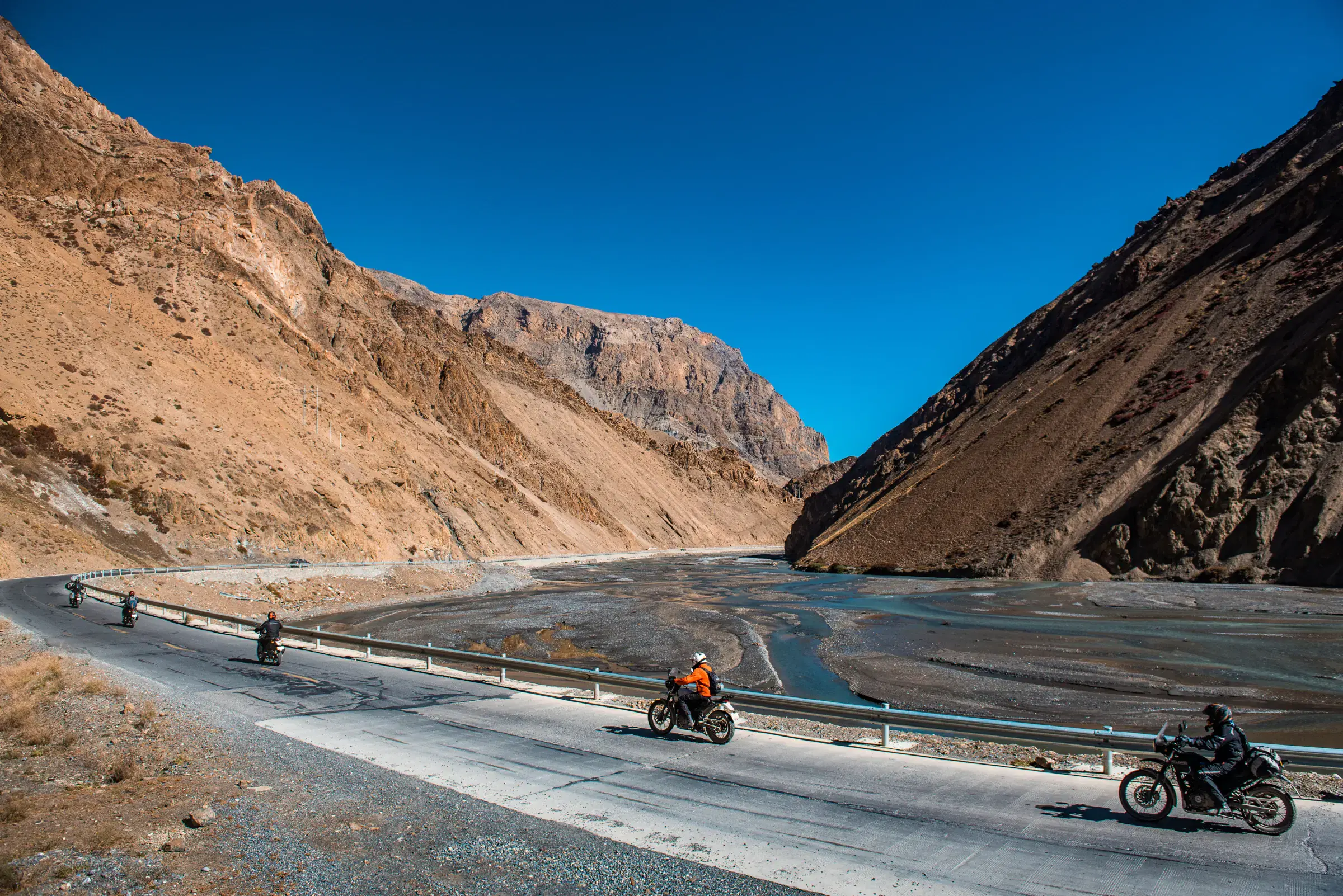 Outdoor vehicle scene featuring a vehicle, rocky terrain, a built structure, and blue sky.