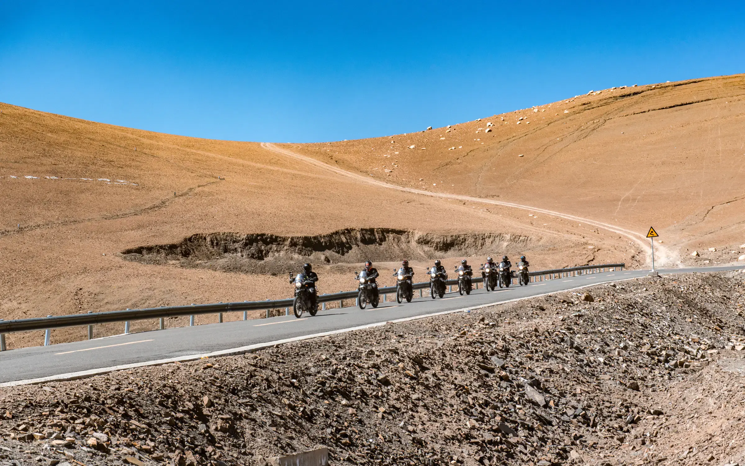 Mountain landscape featuring rocky terrain, a built structure, and blue sky.