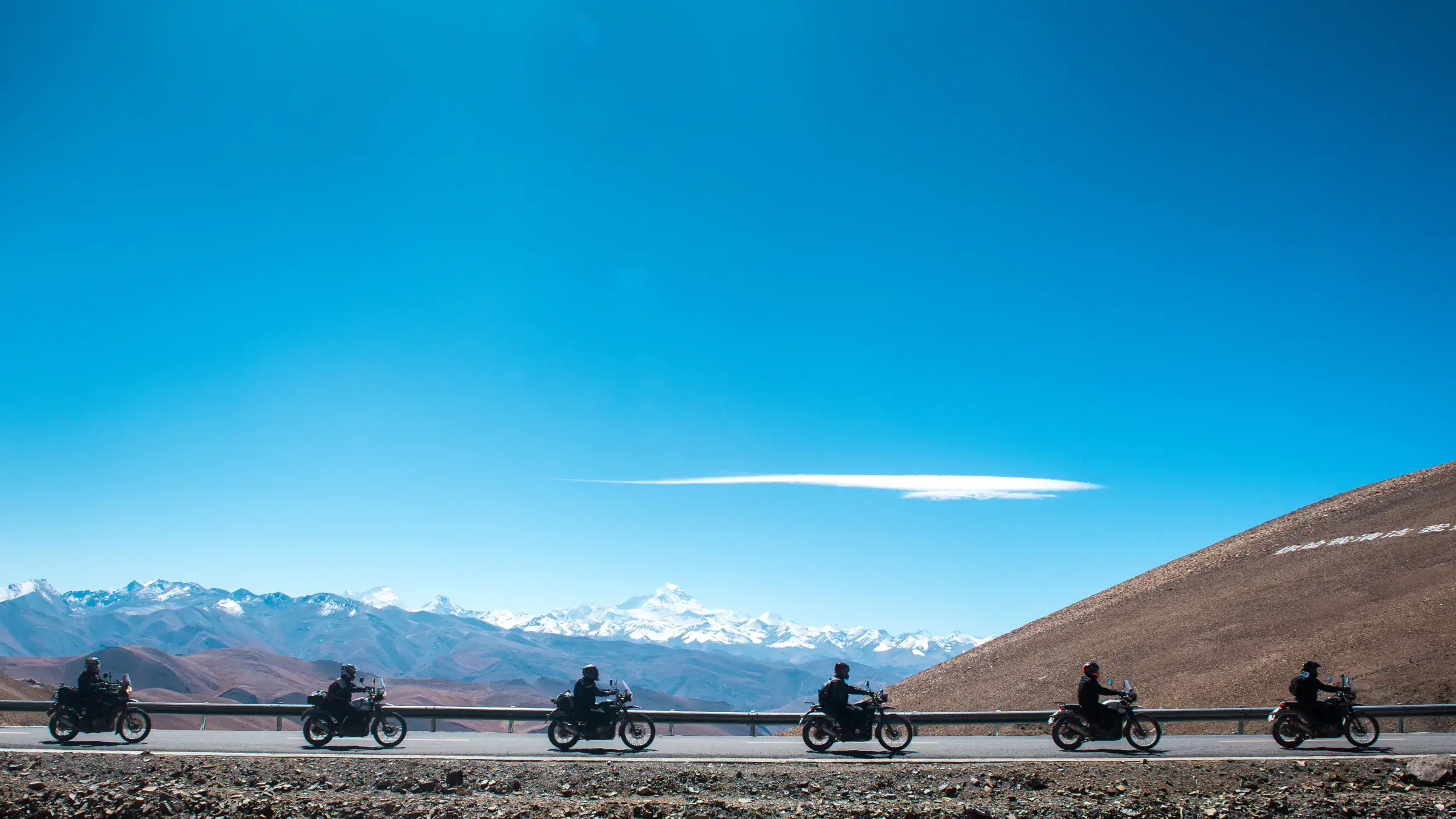 Mountain landscape featuring rocky terrain, a built structure, and cloudy sky.