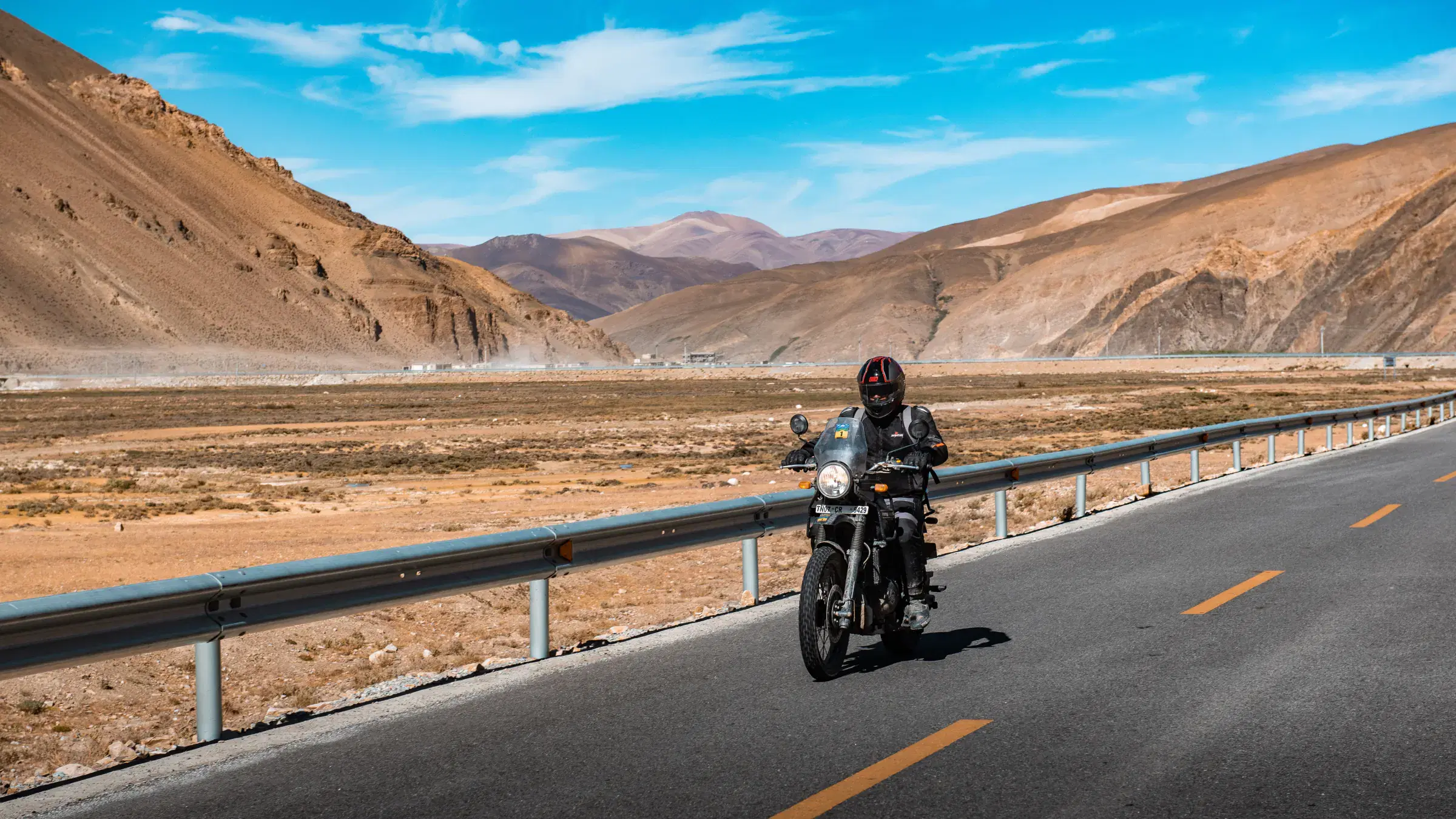 Outdoor scene featuring people, rocky terrain, a built structure, and cloudy sky.