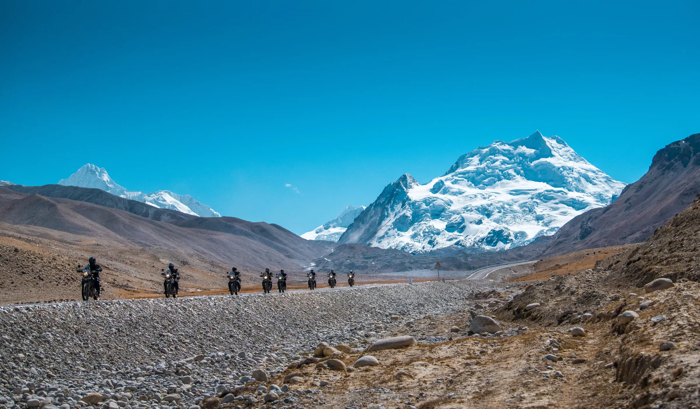 Mountain landscape featuring snowy terrain, water, and blue sky.
