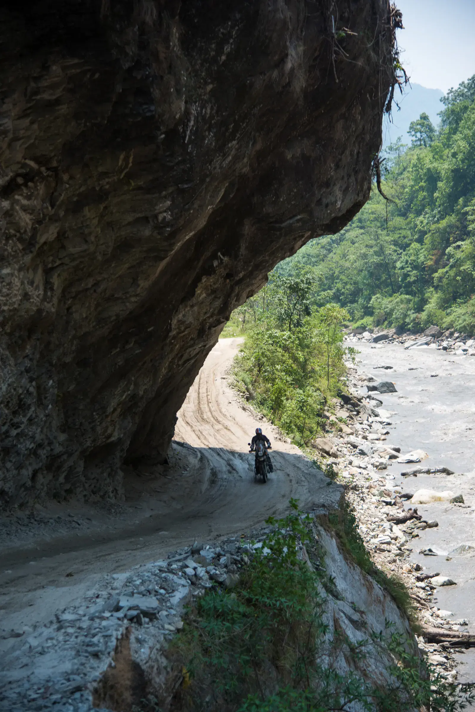 Portrait-oriented Mountain landscape featuring rocky terrain, a built structure, and blue sky.