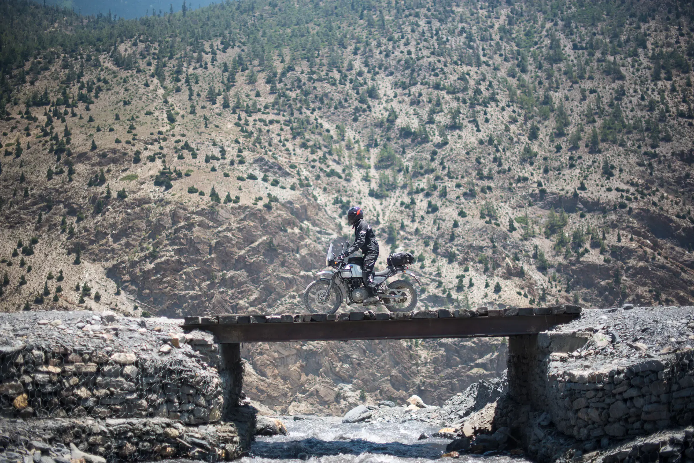 Outdoor scene featuring people, rocky terrain, a built structure, and blue sky.