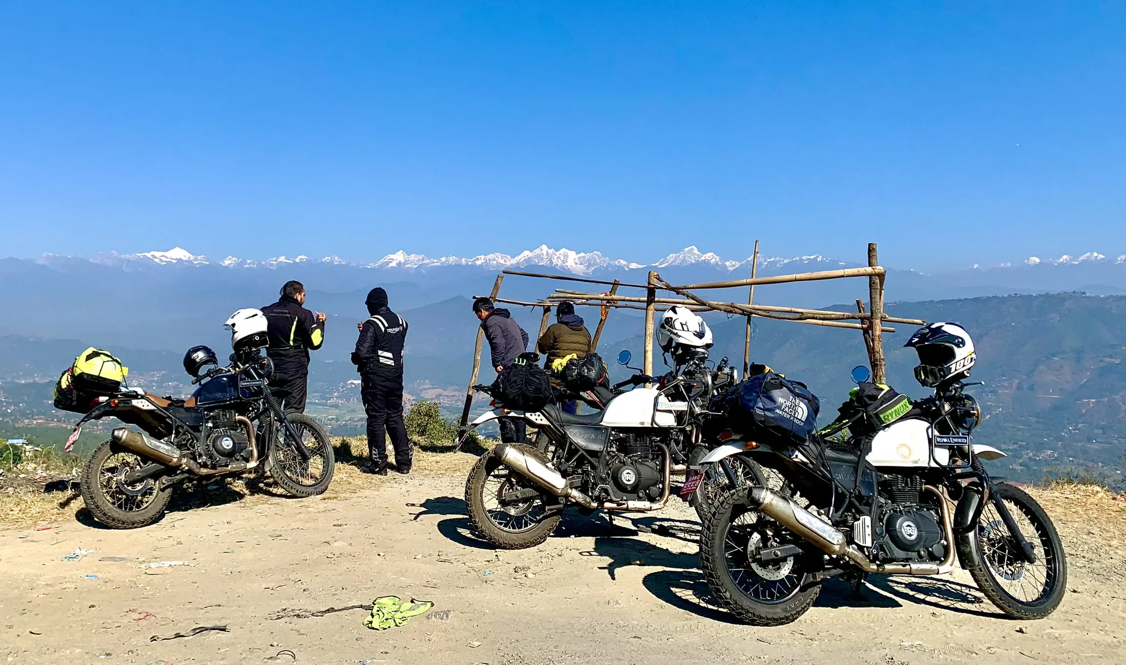 Outdoor adventure scene featuring people, a vehicle, rocky terrain, and blue sky.