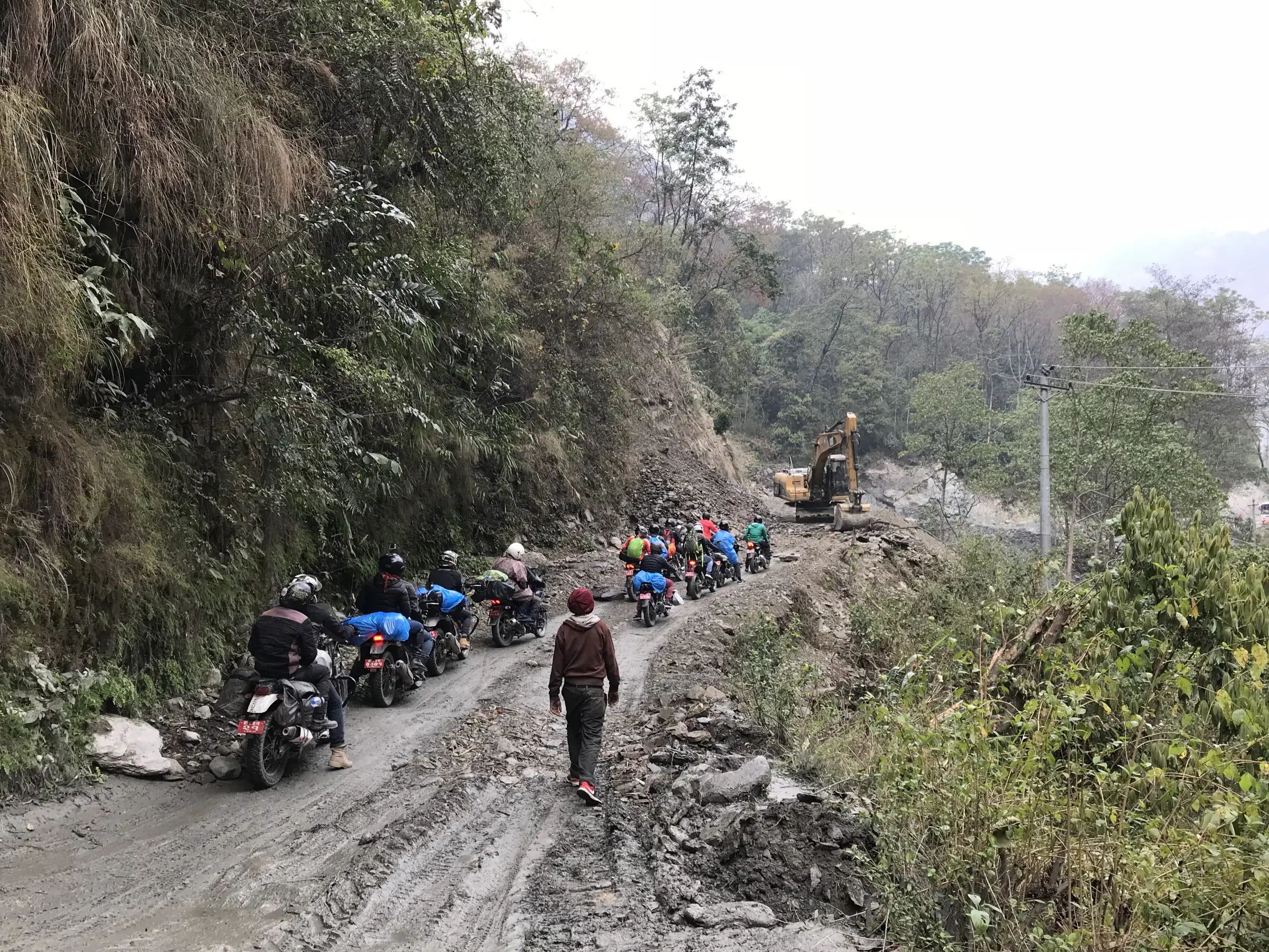 Outdoor adventure scene featuring people, a vehicle, rocky terrain, and a built structure.