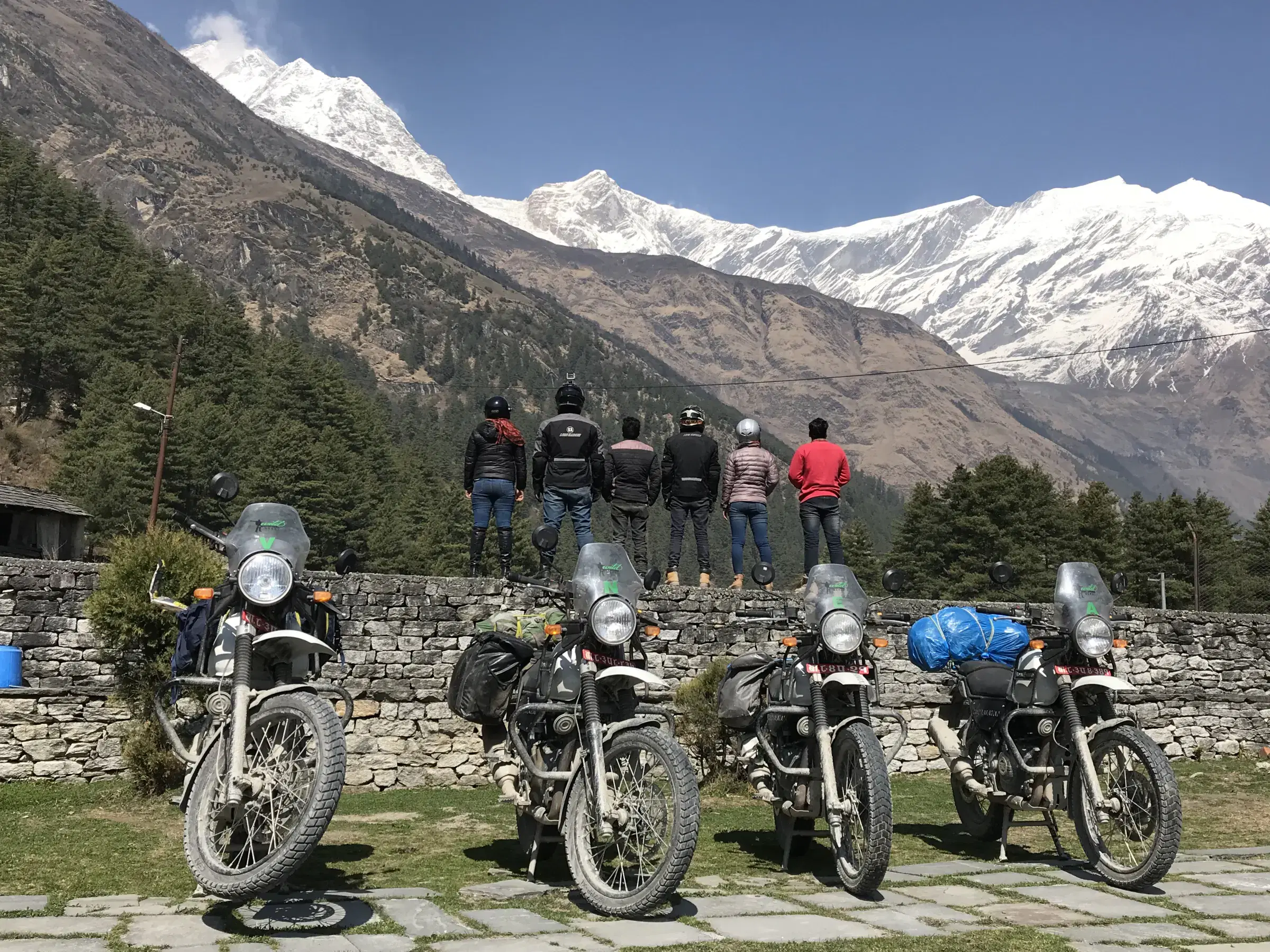 Outdoor scene featuring people, rocky terrain, cloudy sky, and greenery.