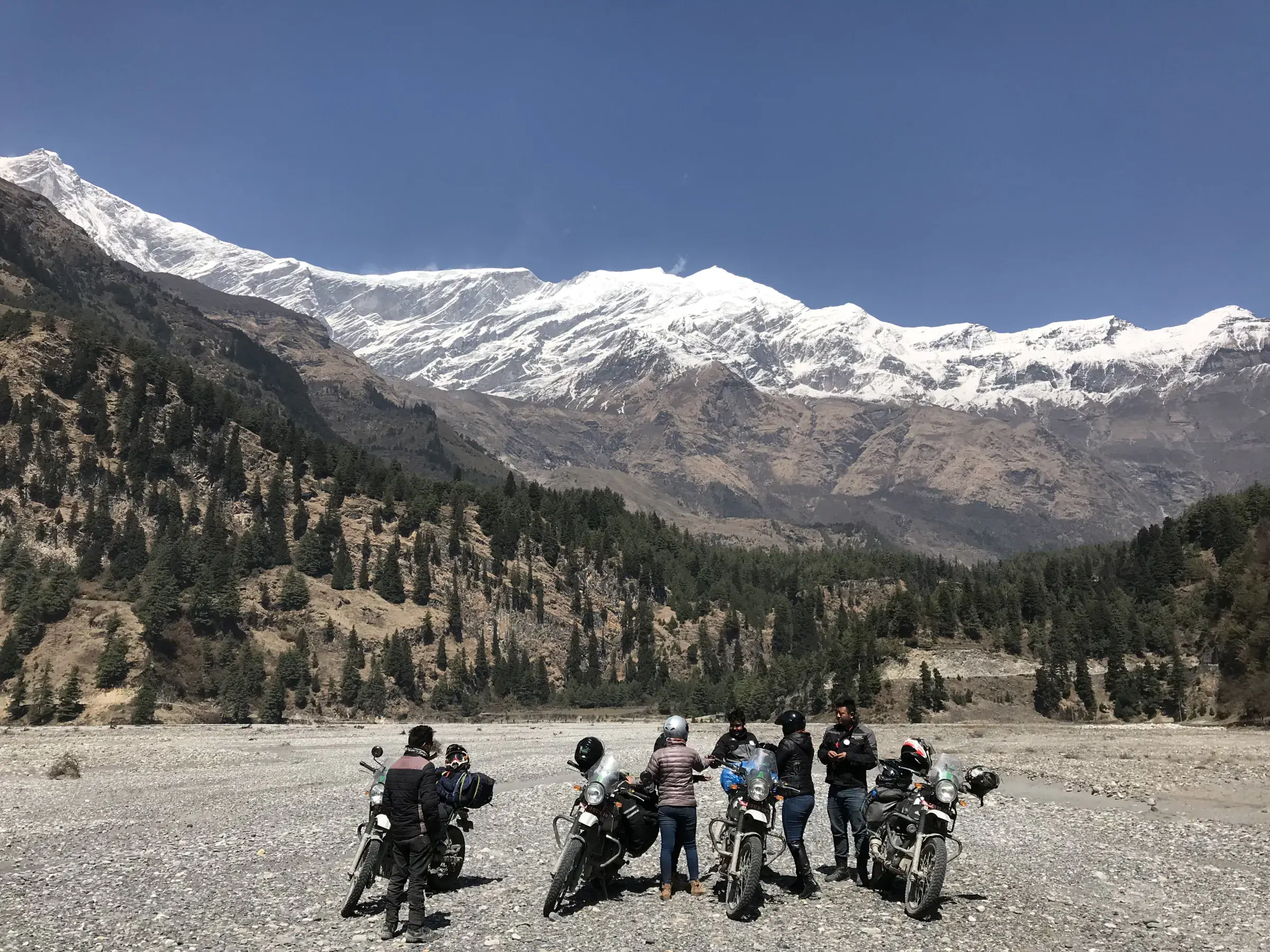 Outdoor scene featuring people, snowy terrain, and blue sky.