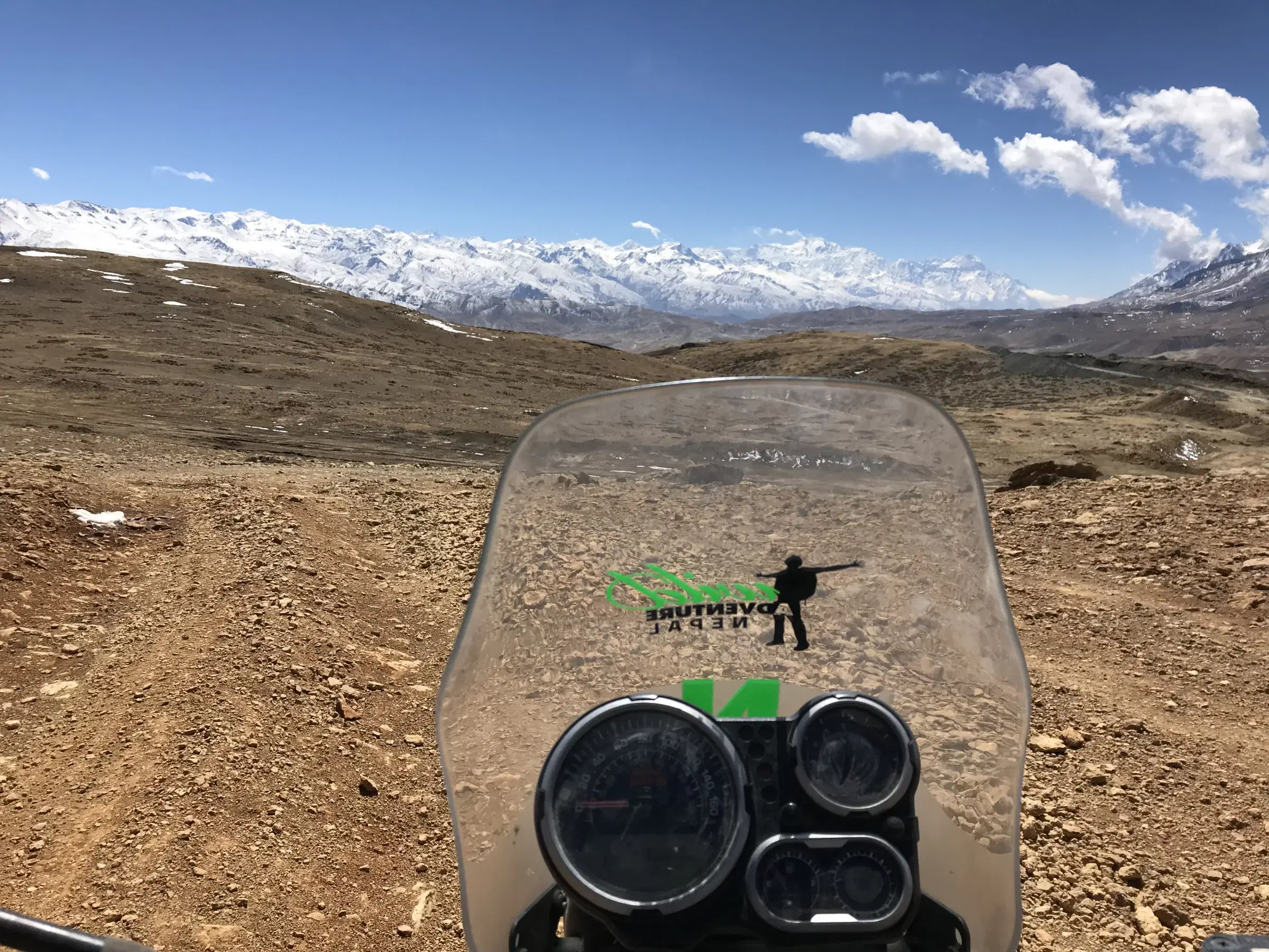 Mountain landscape featuring snowy terrain, water, a built structure, and cloudy sky.