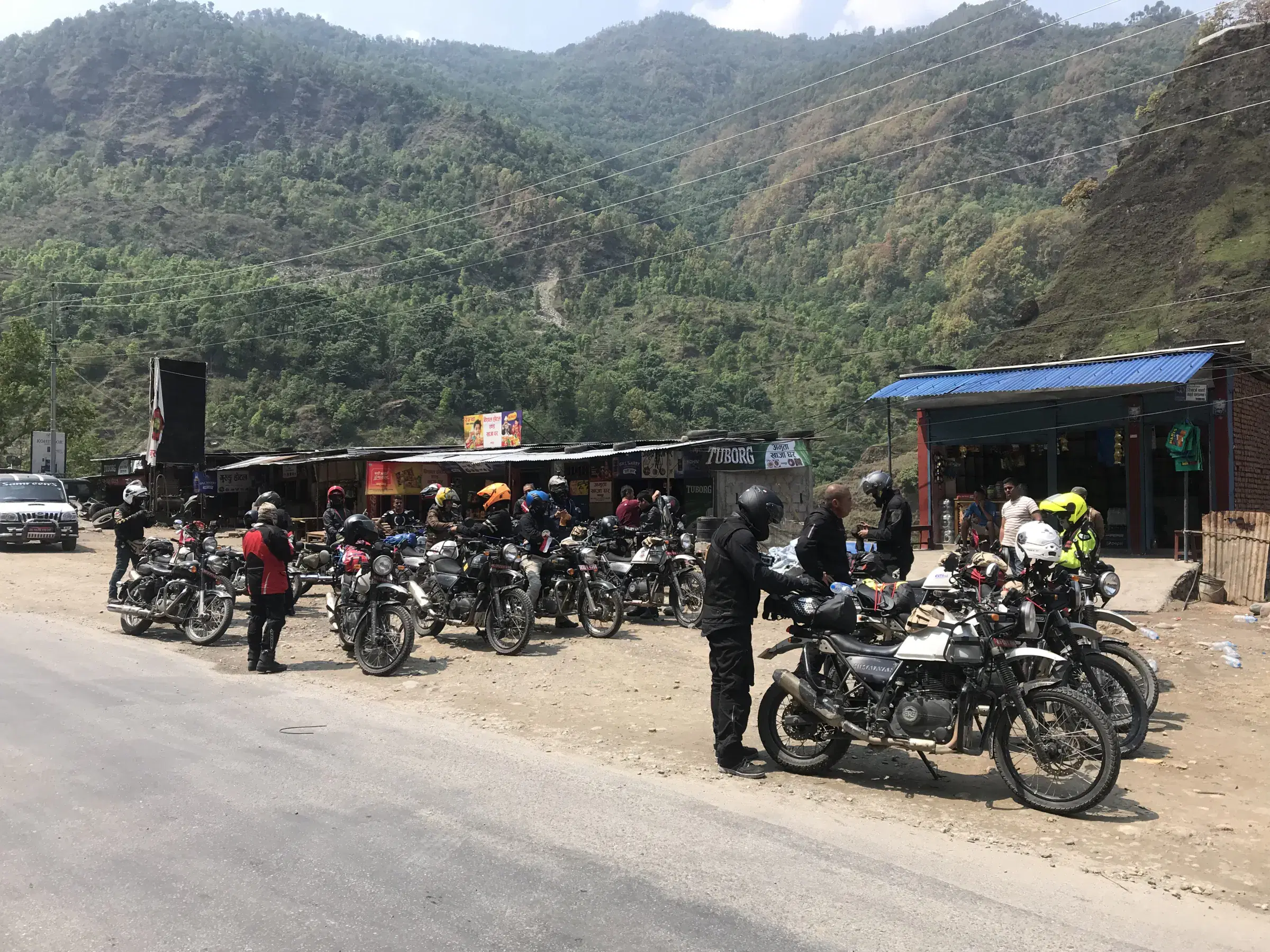 Outdoor adventure scene featuring people, a vehicle, rocky terrain, and cloudy sky.