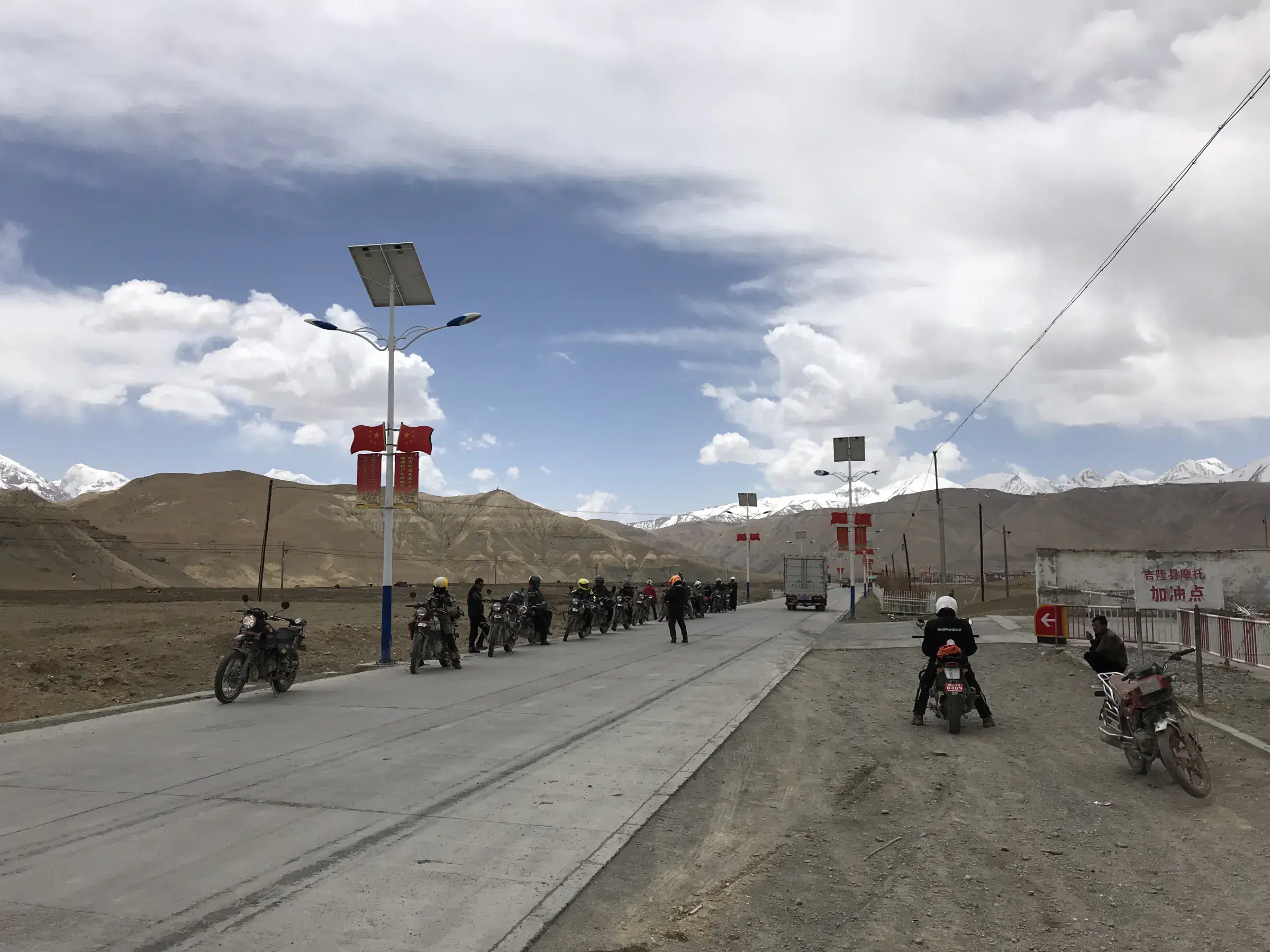 Outdoor adventure scene featuring people, a vehicle, rocky terrain, and cloudy sky.