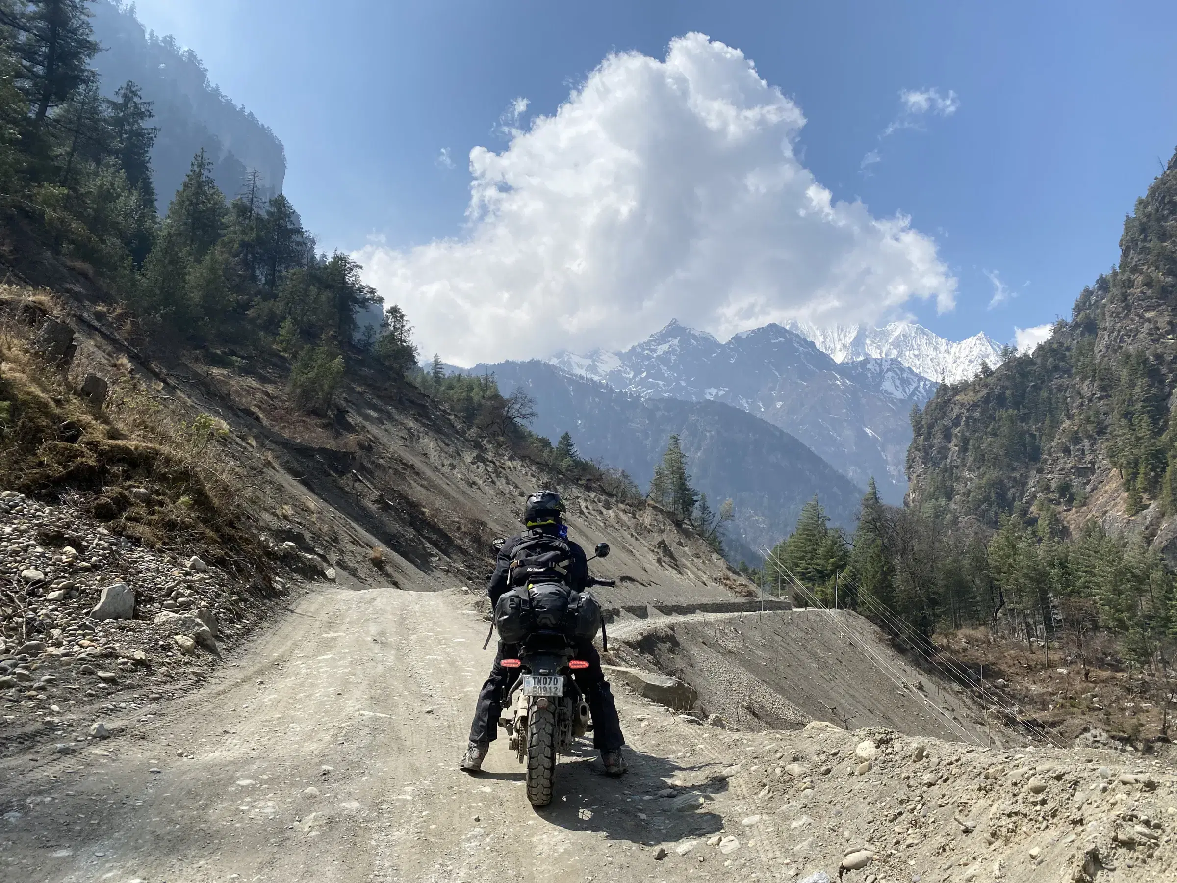 Outdoor scene featuring people, rocky terrain, and cloudy sky.