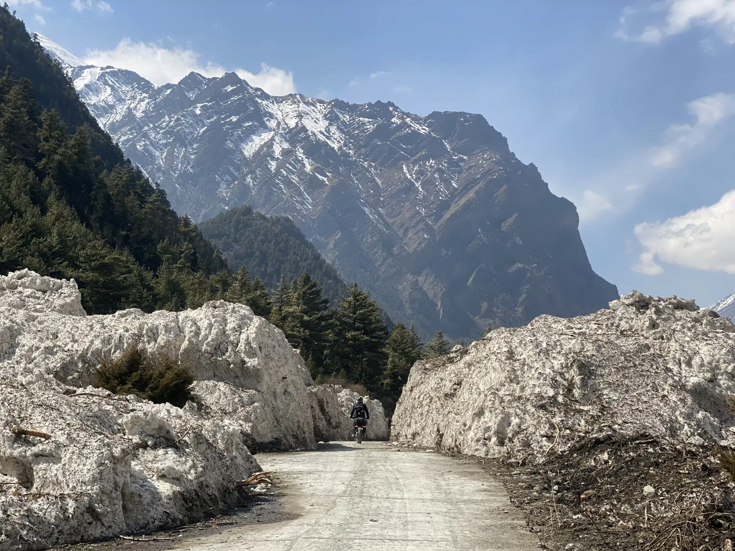 Mountain landscape featuring rocky terrain, water, a built structure, and cloudy sky.
