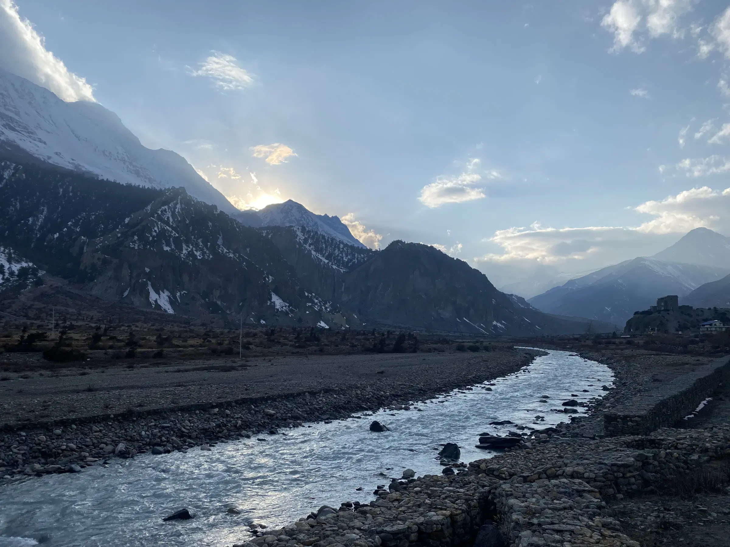 Mountain landscape featuring rocky terrain, a built structure, and cloudy sky.