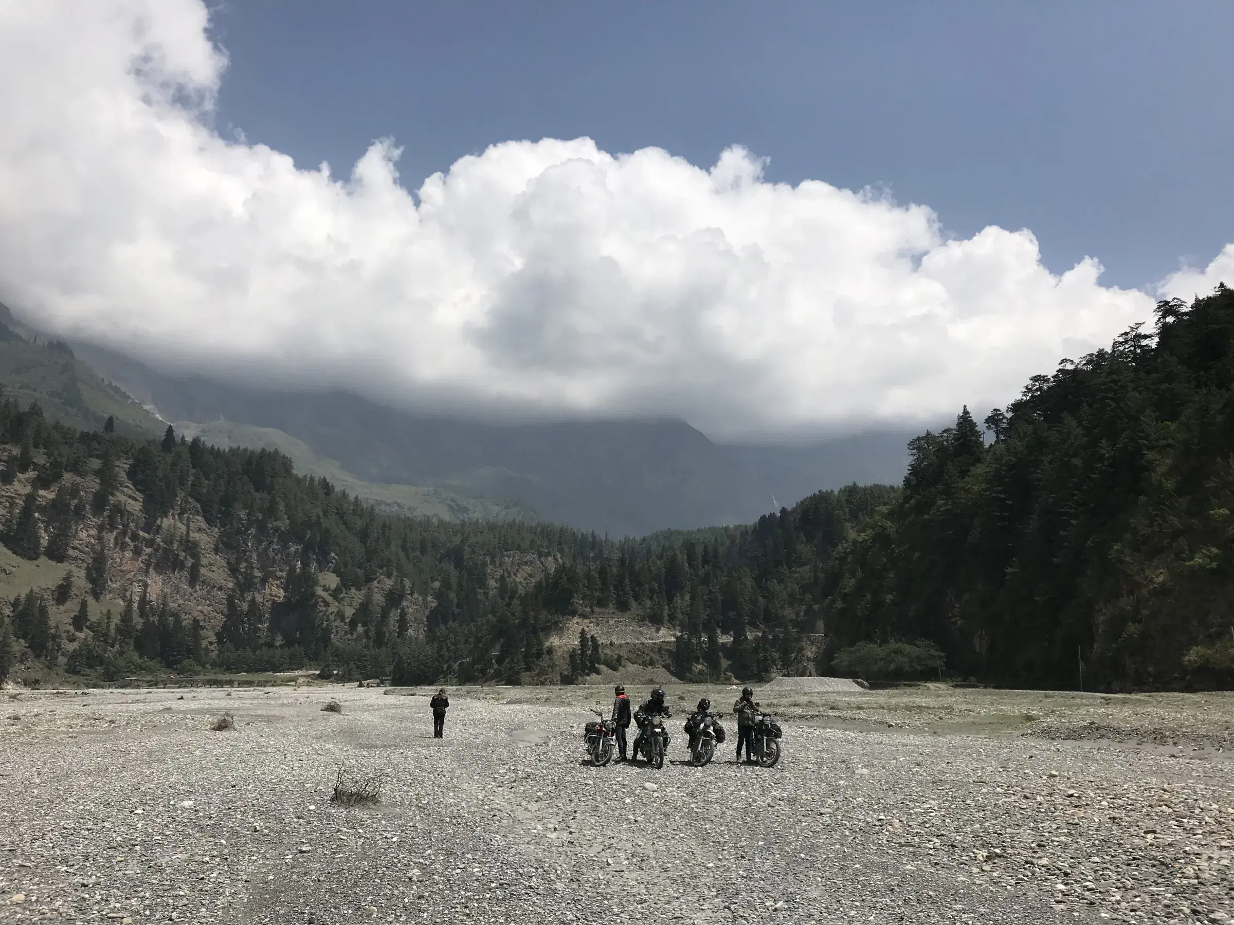 Mountain landscape featuring rocky terrain, a built structure, cloudy sky, and greenery.