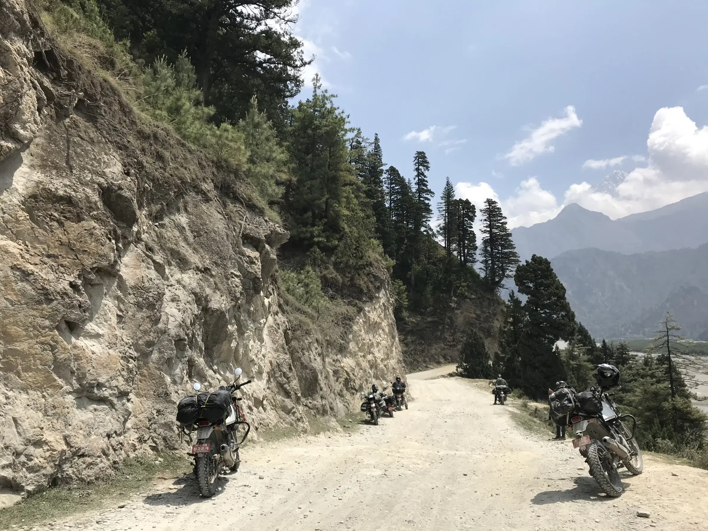 Outdoor scene featuring people, rocky terrain, a built structure, and cloudy sky.