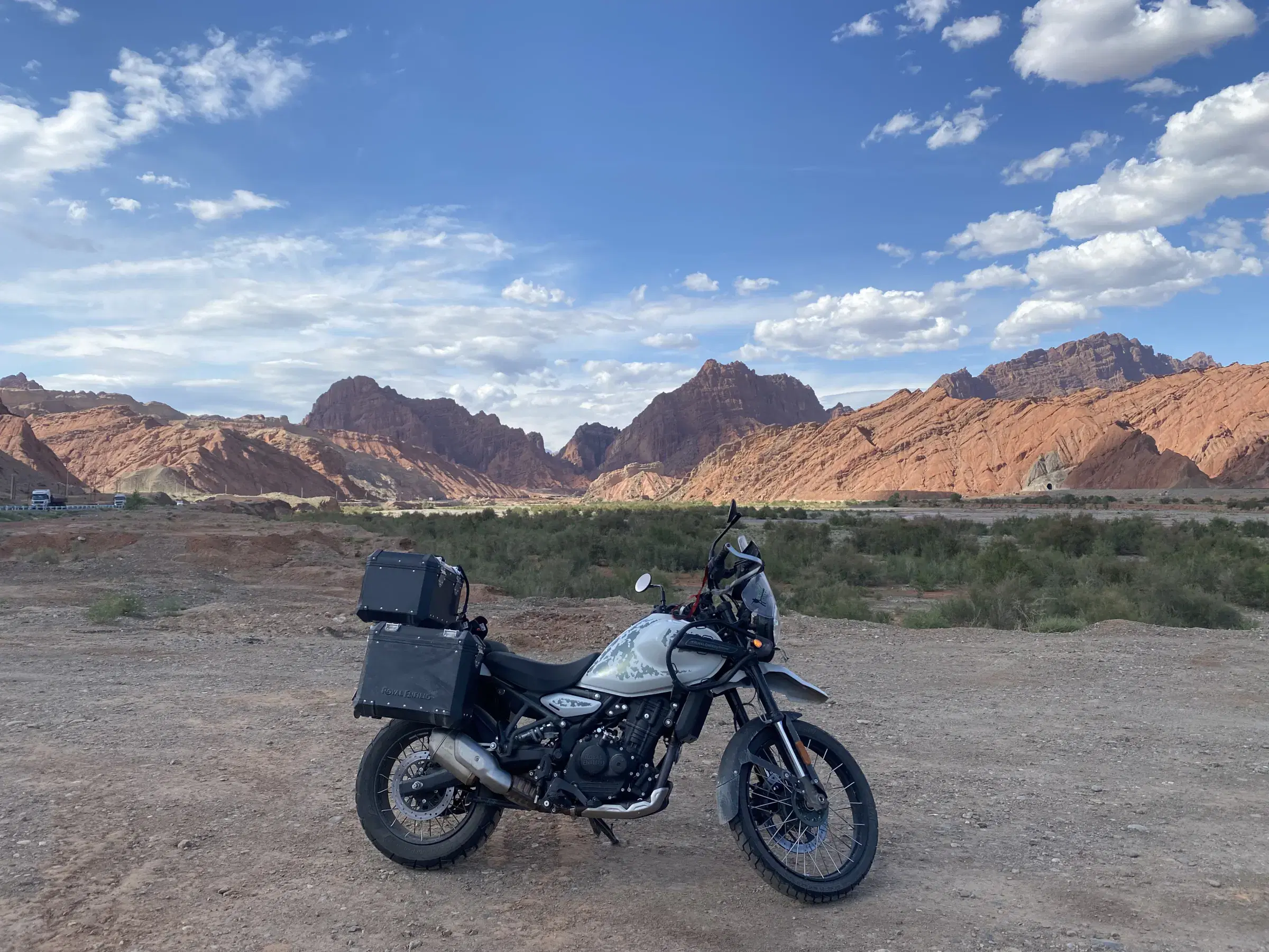 Outdoor adventure scene featuring people, a vehicle, rocky terrain, and cloudy sky.
