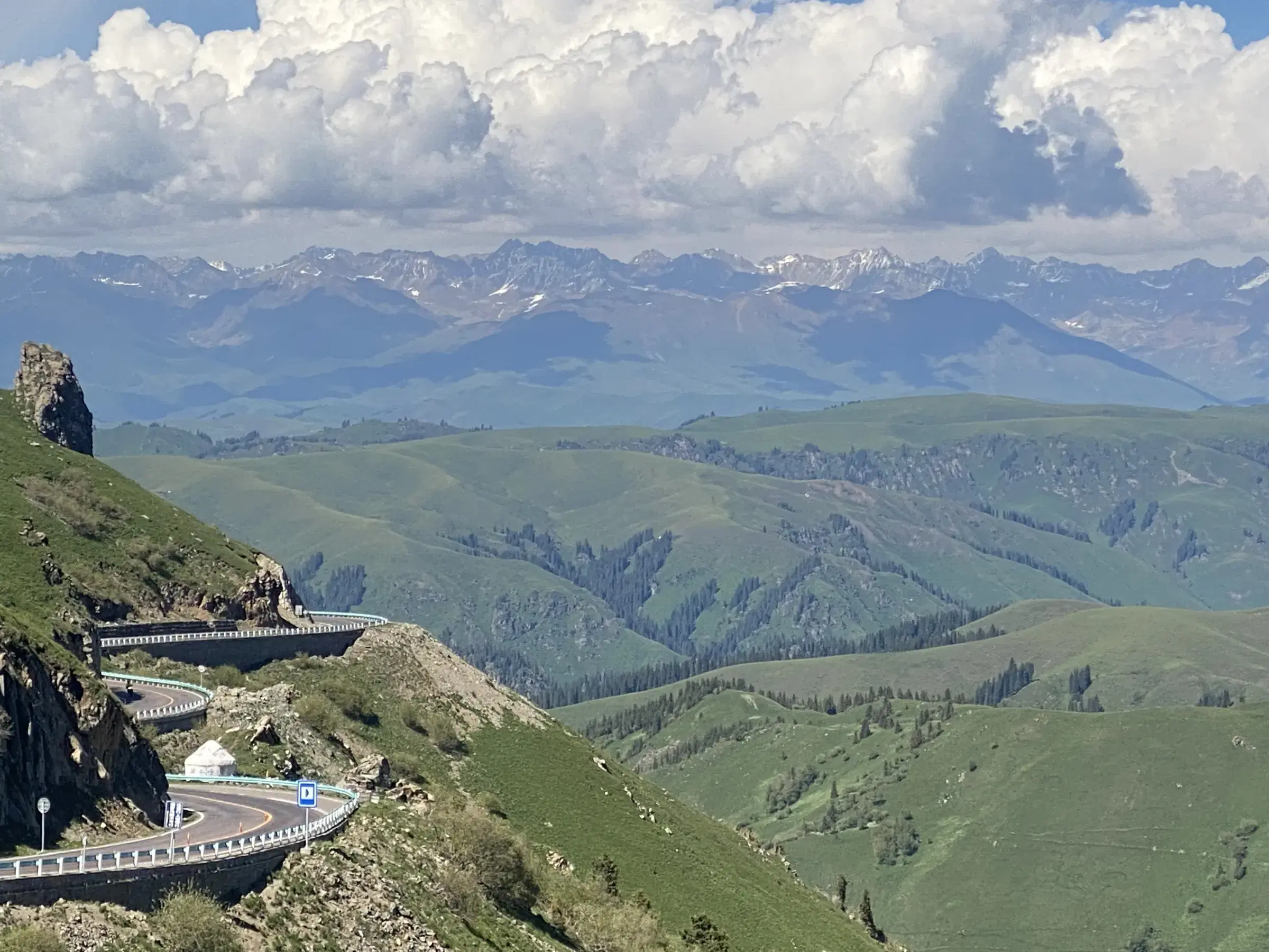 Mountain landscape featuring rocky terrain, cloudy sky, and greenery.
